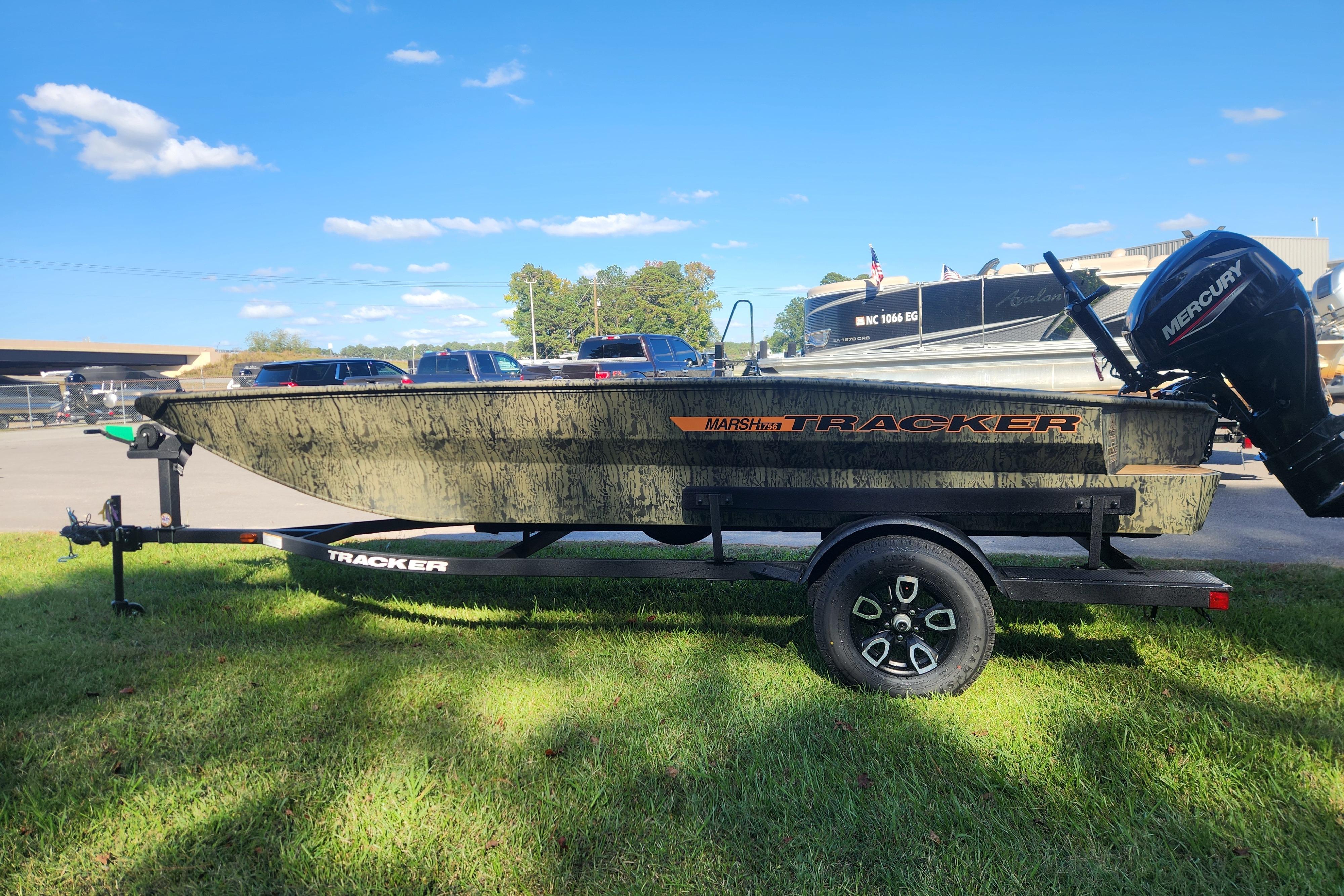2026 Tracker Grizzly 1756 T Marsh boat on trailer, parked on grass under blue sky.