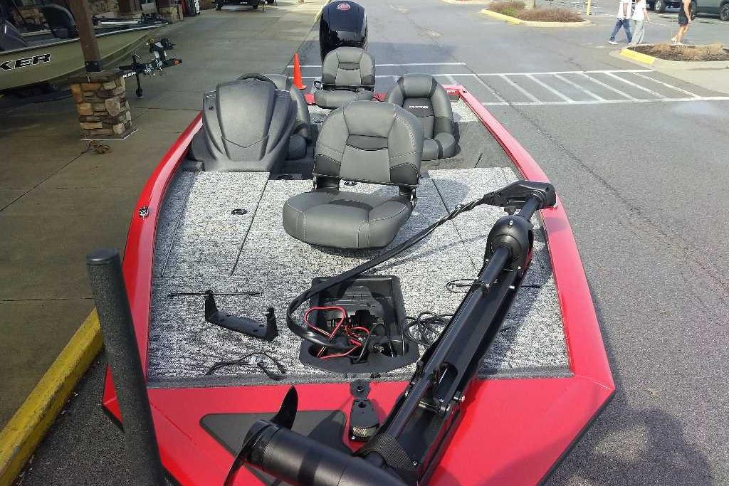 2026 Tracker Pro Team 195 boat with red exterior and gray seating, parked outdoors.