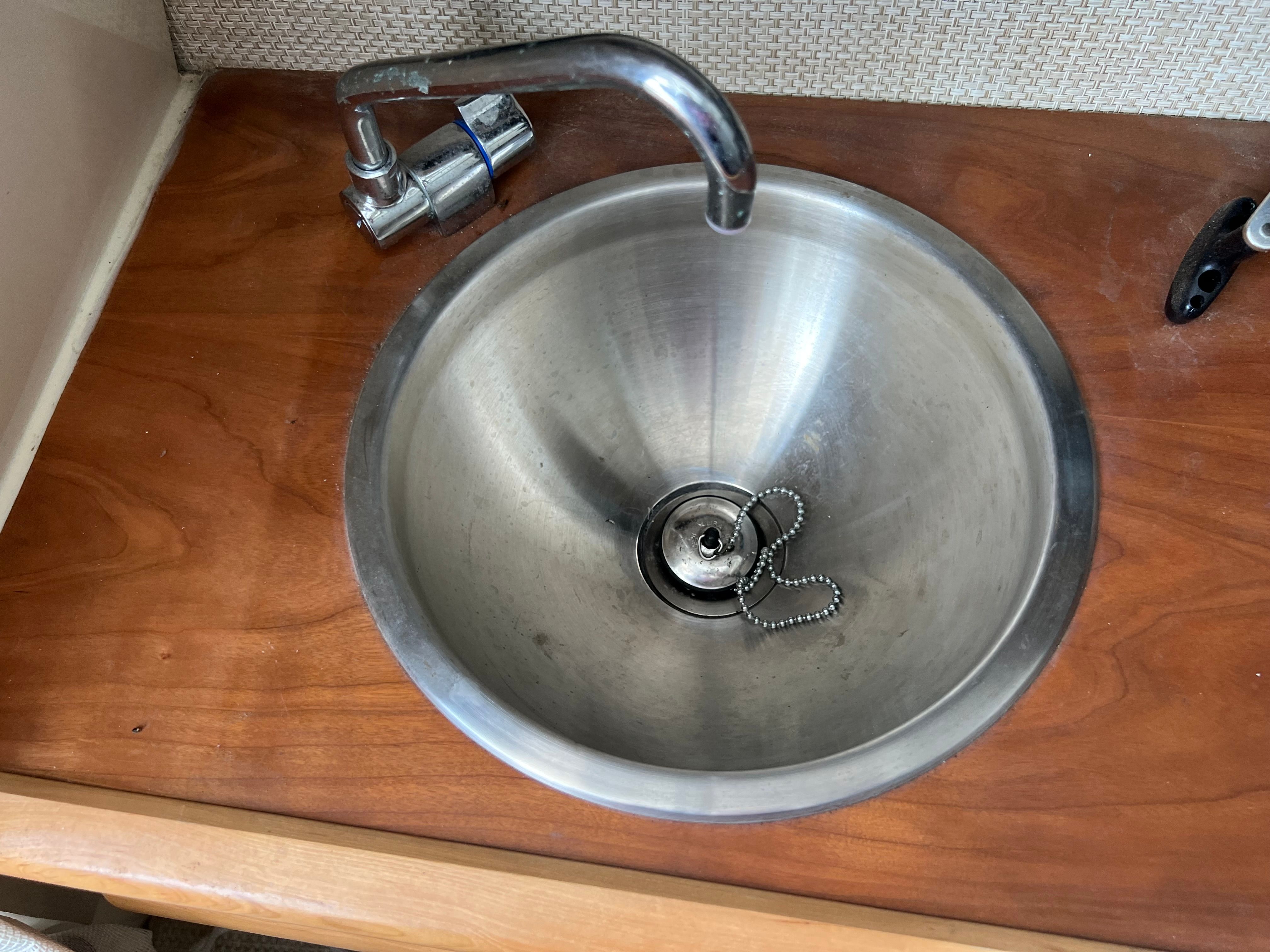 A stainless steel sink with a faucet on a wooden countertop.