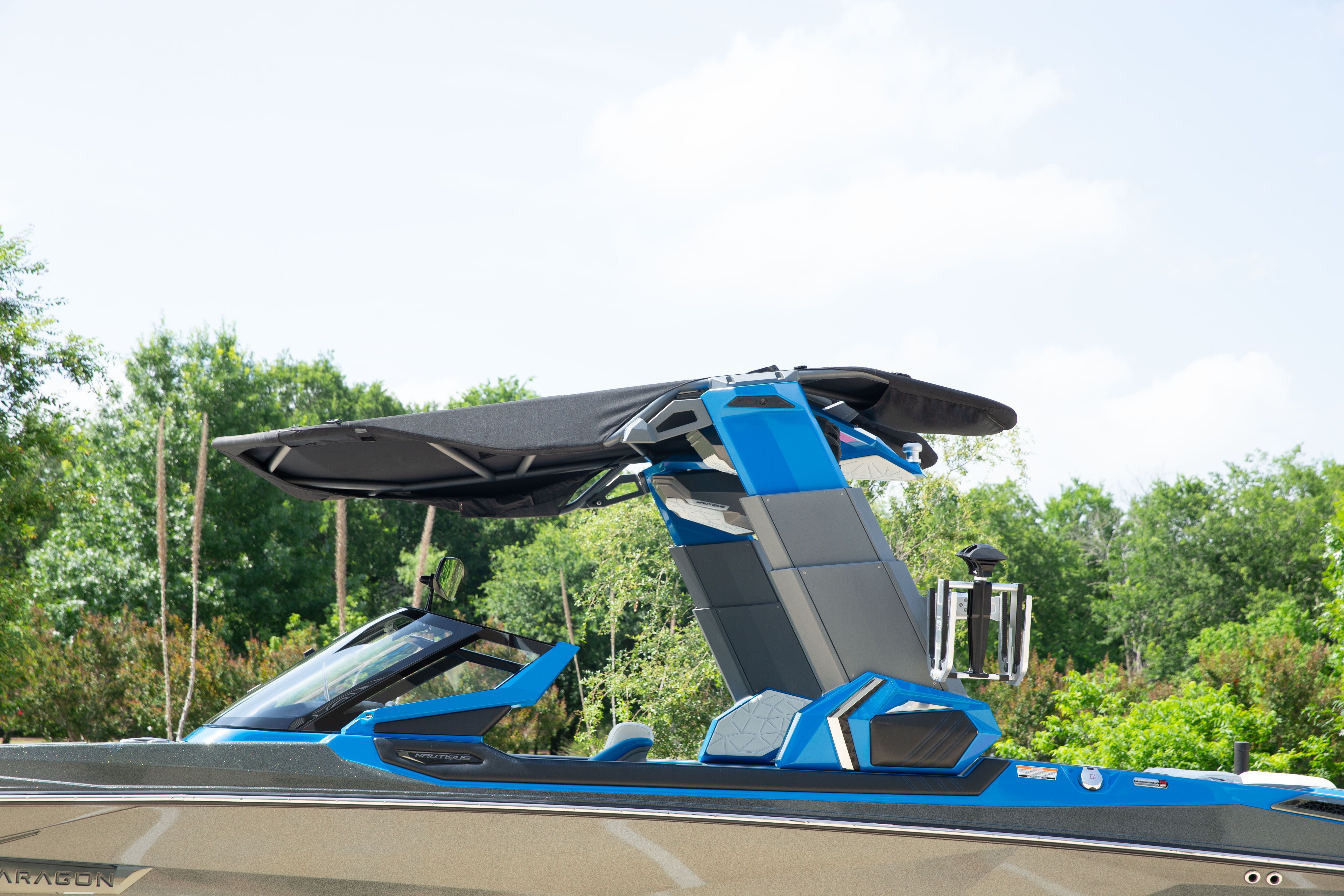 A modern boat with blue and black design, surrounded by green trees.