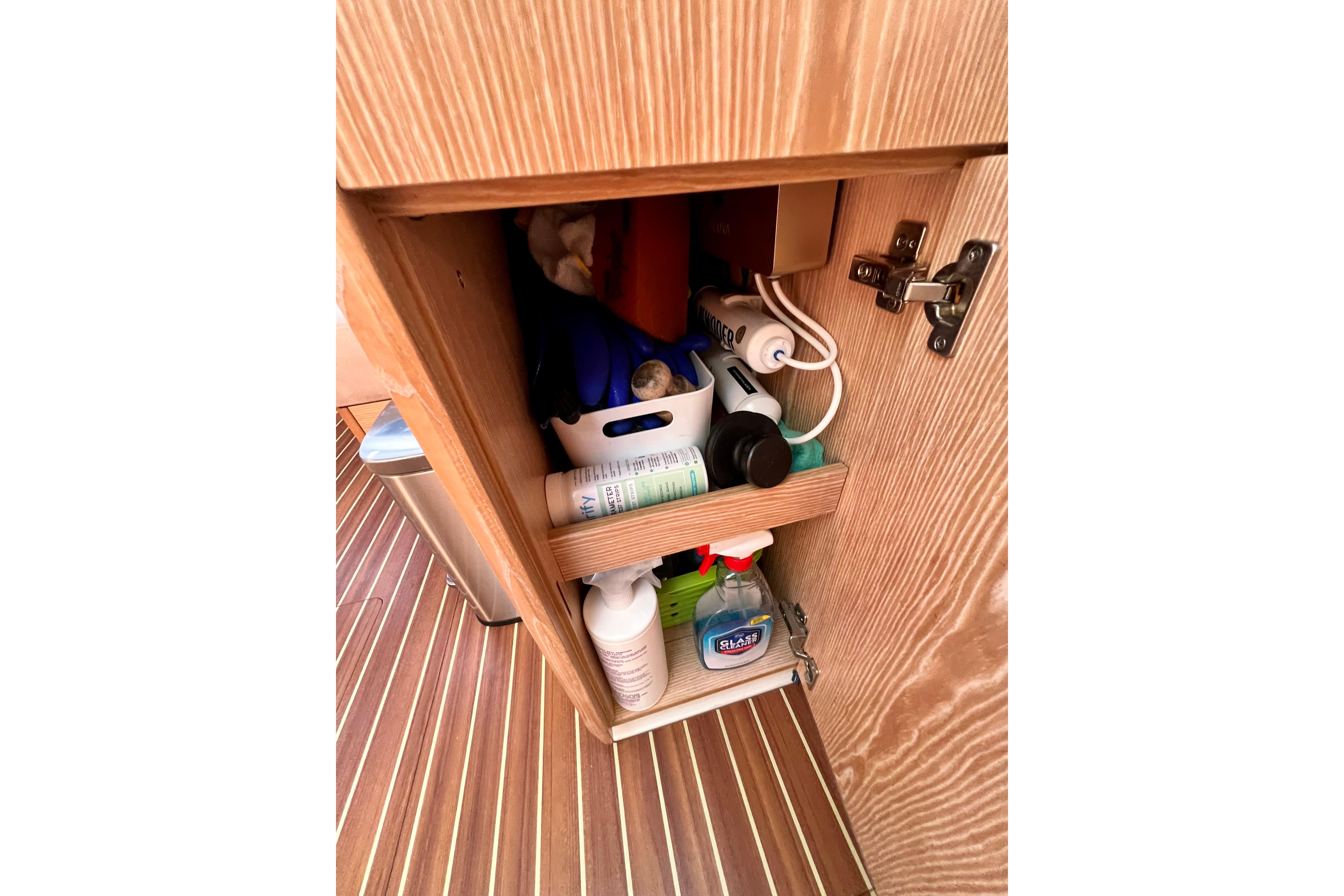 Cabinet storage on 2016 Hanse 455 yacht with cleaning supplies and toiletries.