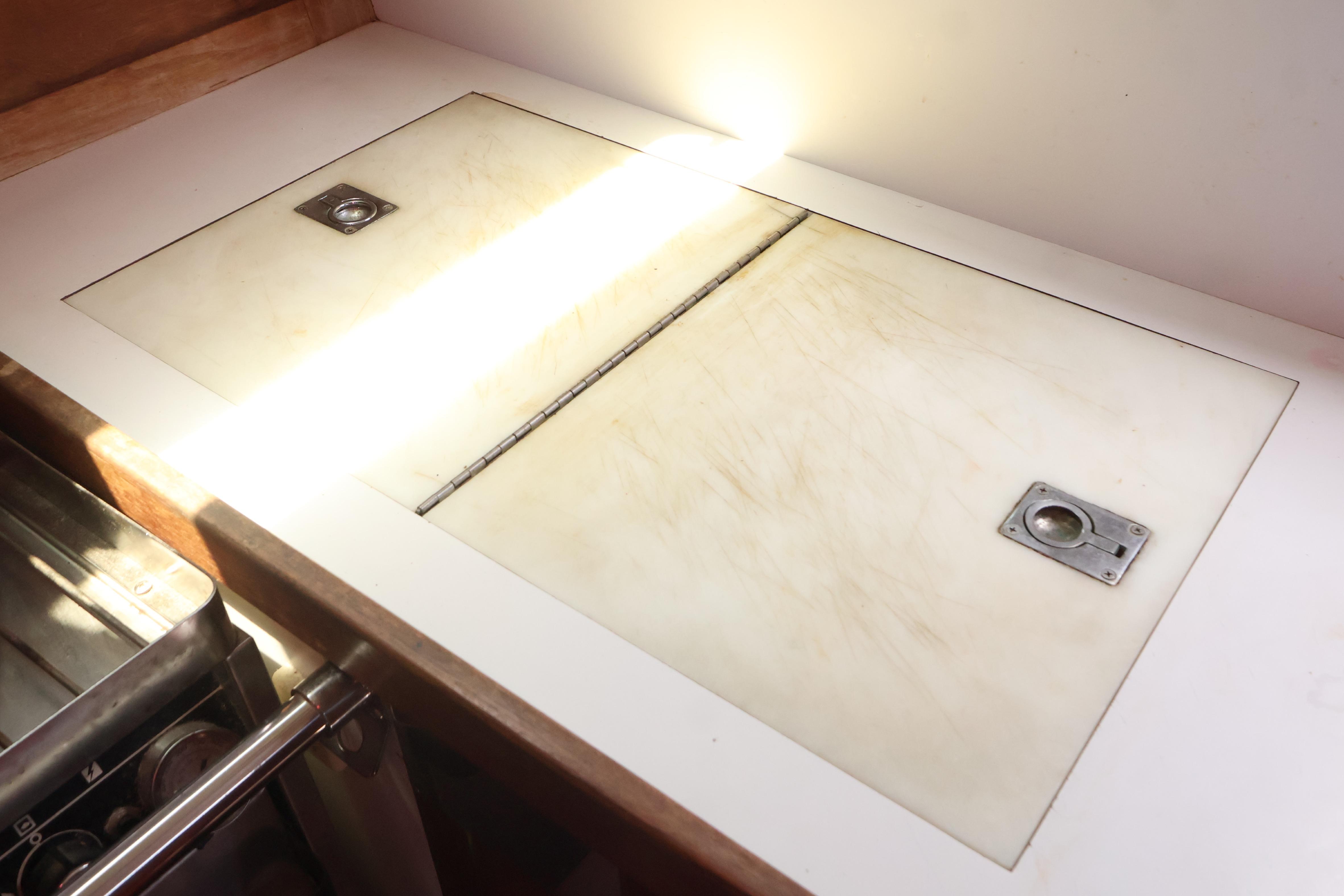 1989 J Boat J 40 galley countertop with storage compartments and metal handles.