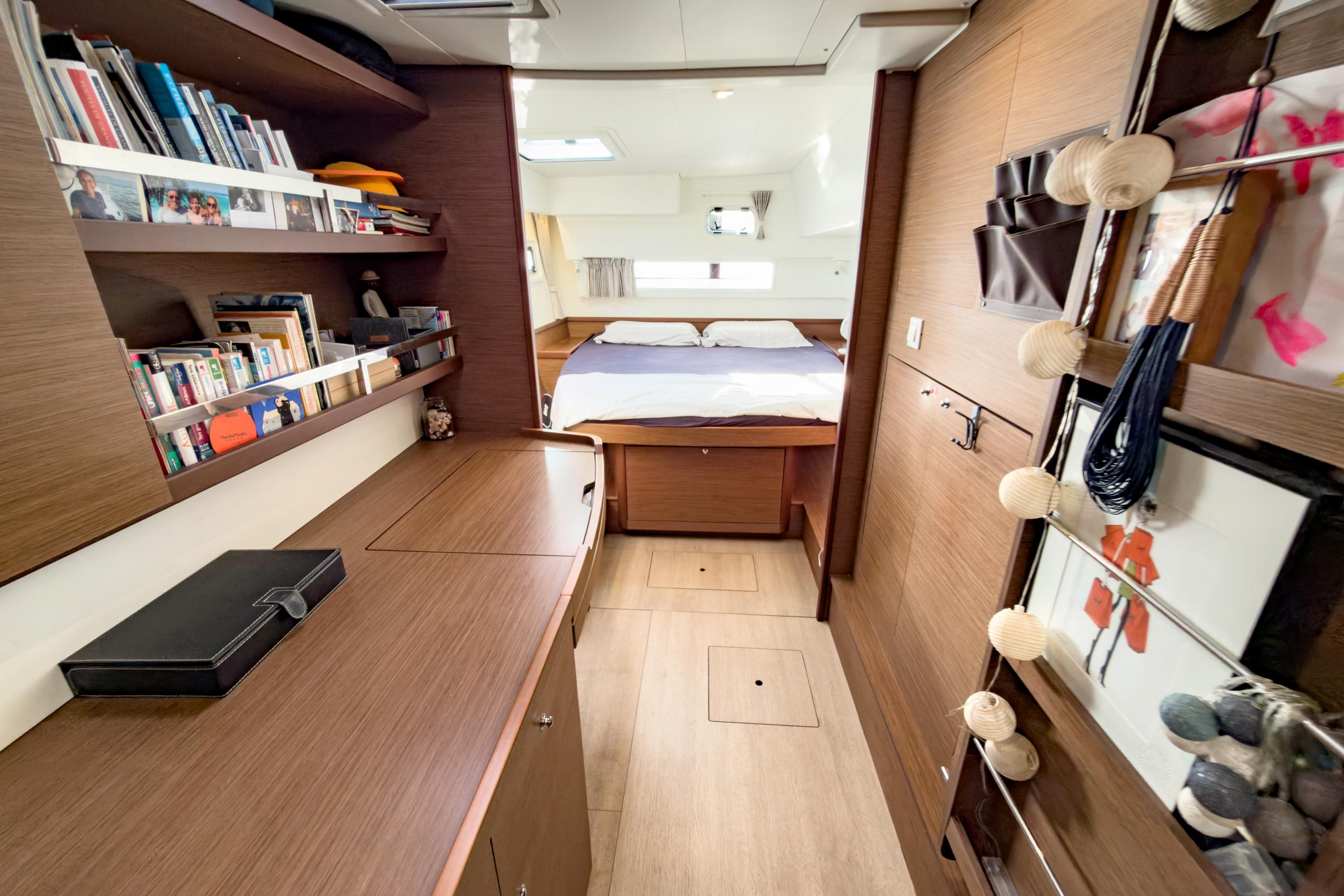 Luxurious interior of a 2022 Lagoon 42 catamaran with cozy bedroom and wooden furnishings.