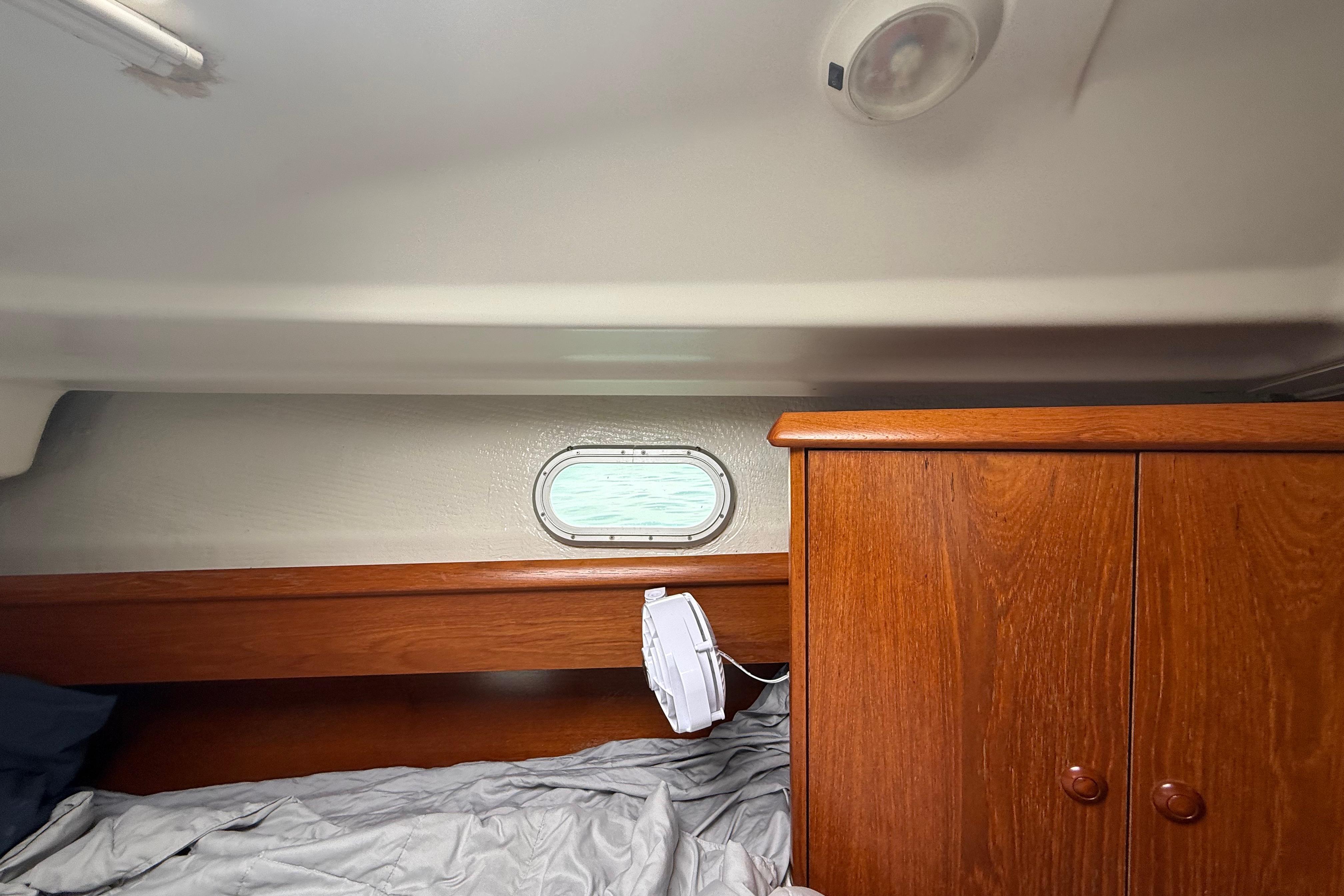 Interior cabin of 2003 Jeanneau Sun Odyssey 37 with wooden cabinetry and bedding.
