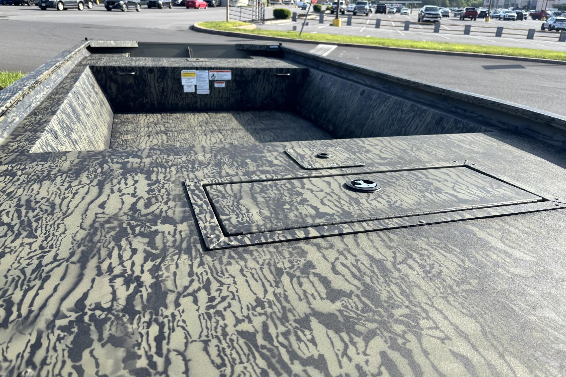 2026 Tracker Grizzly 1648 Utility boat with camouflage pattern in a parking lot.
