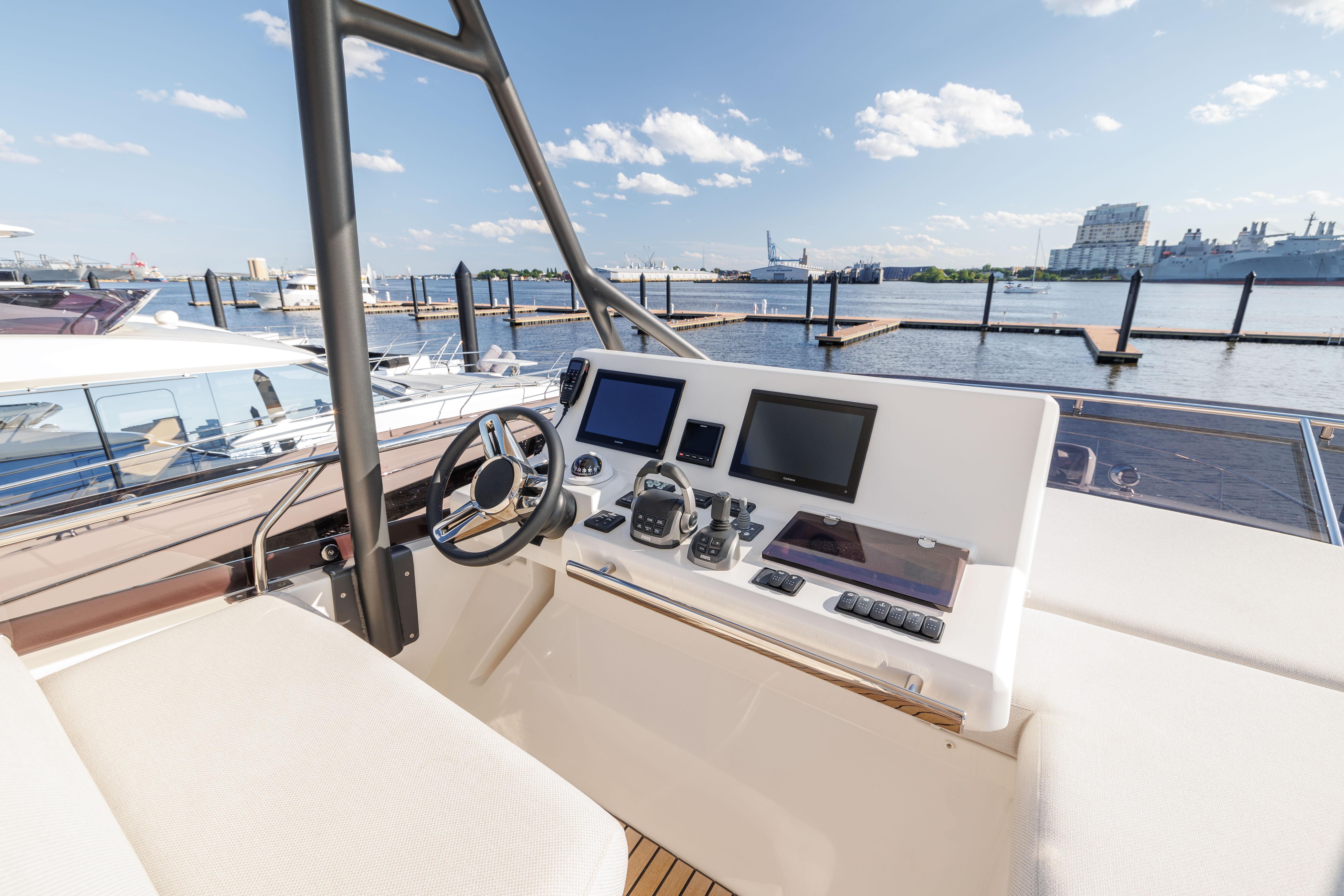 2024 Prestige 520 yacht helm station with modern navigation equipment, docked at a marina.