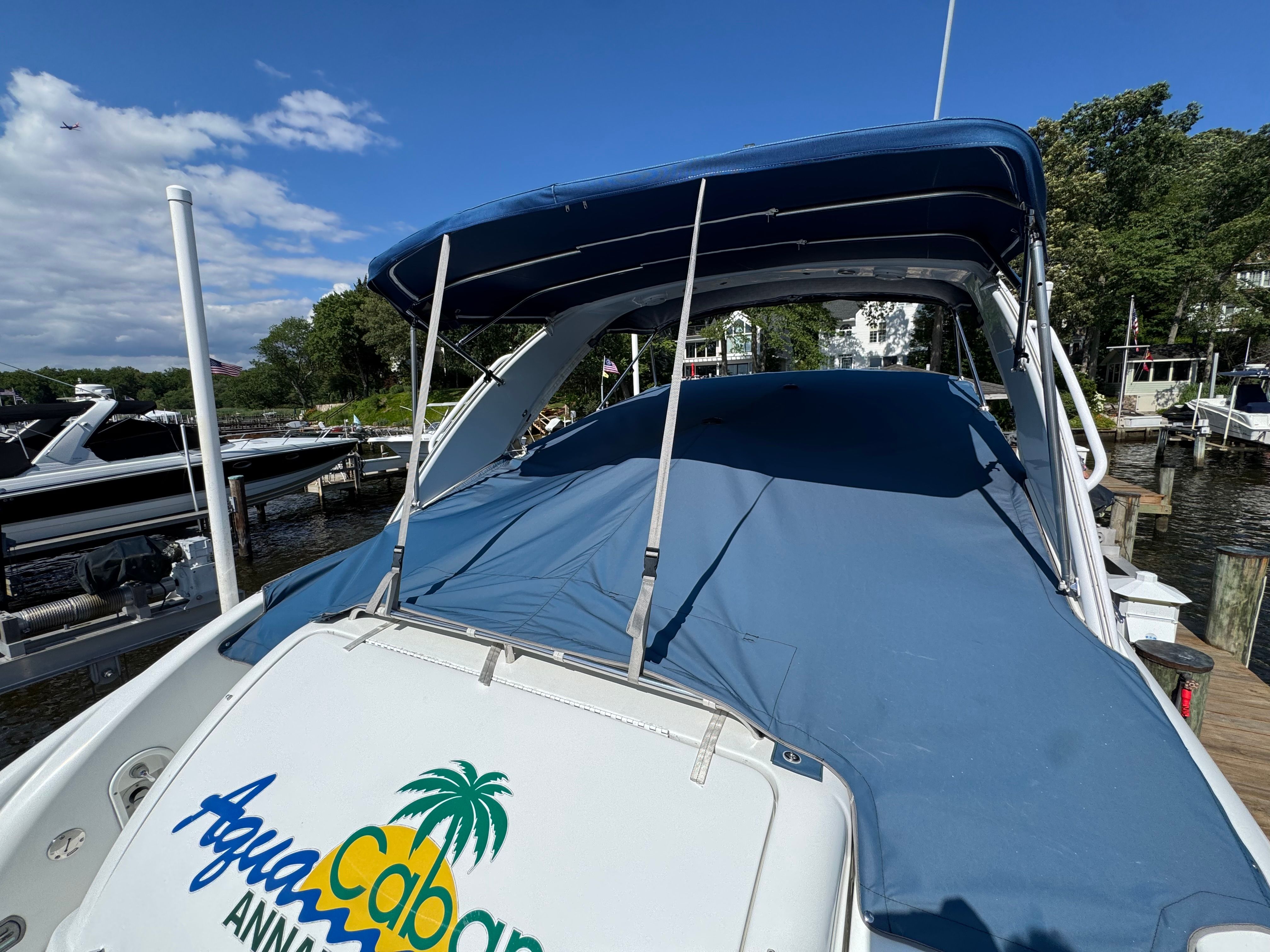 A boat with a blue cover docked at a sunny pier.