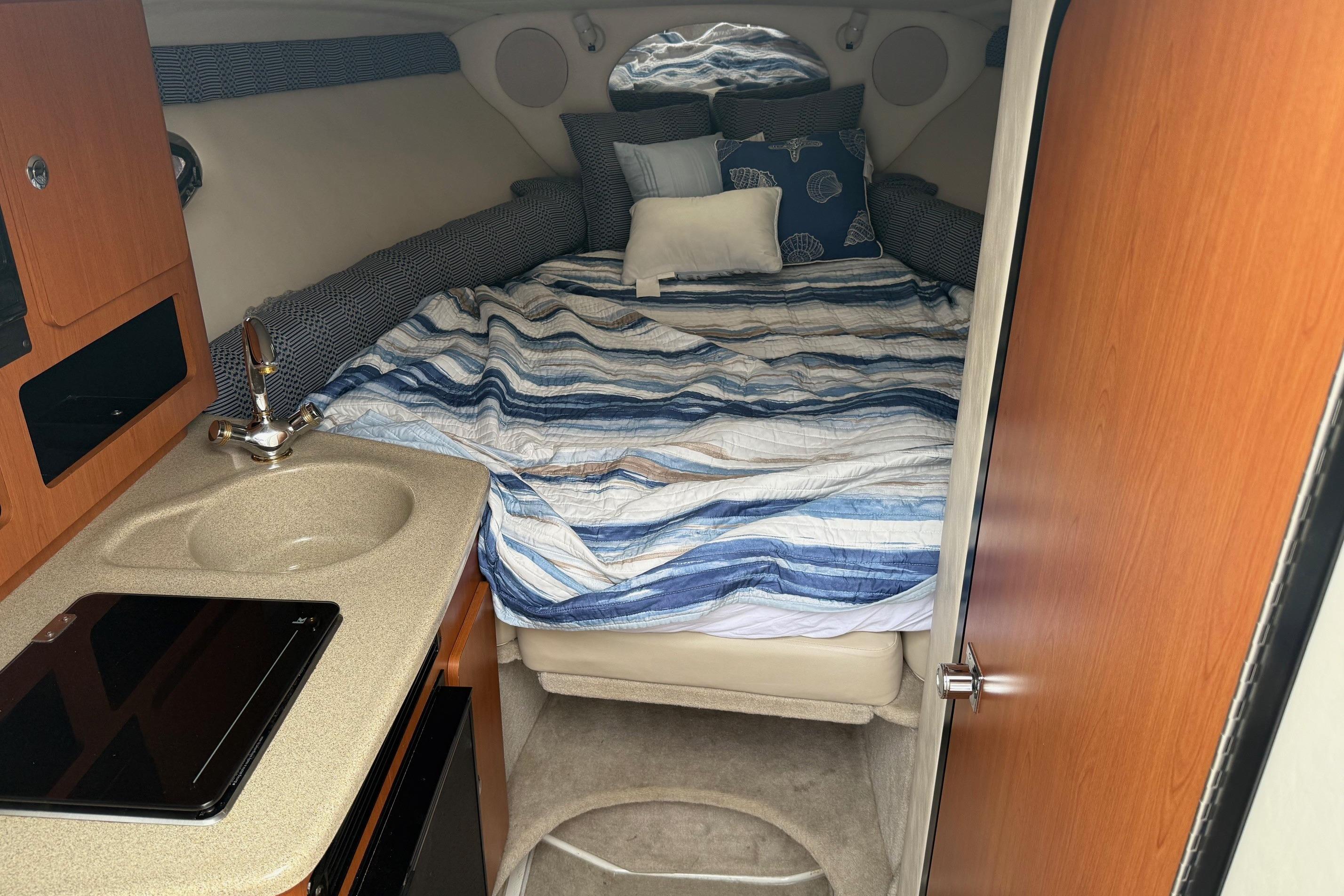 2005 Crownline 250 CR cabin interior with bed, sink, and compact kitchen area.