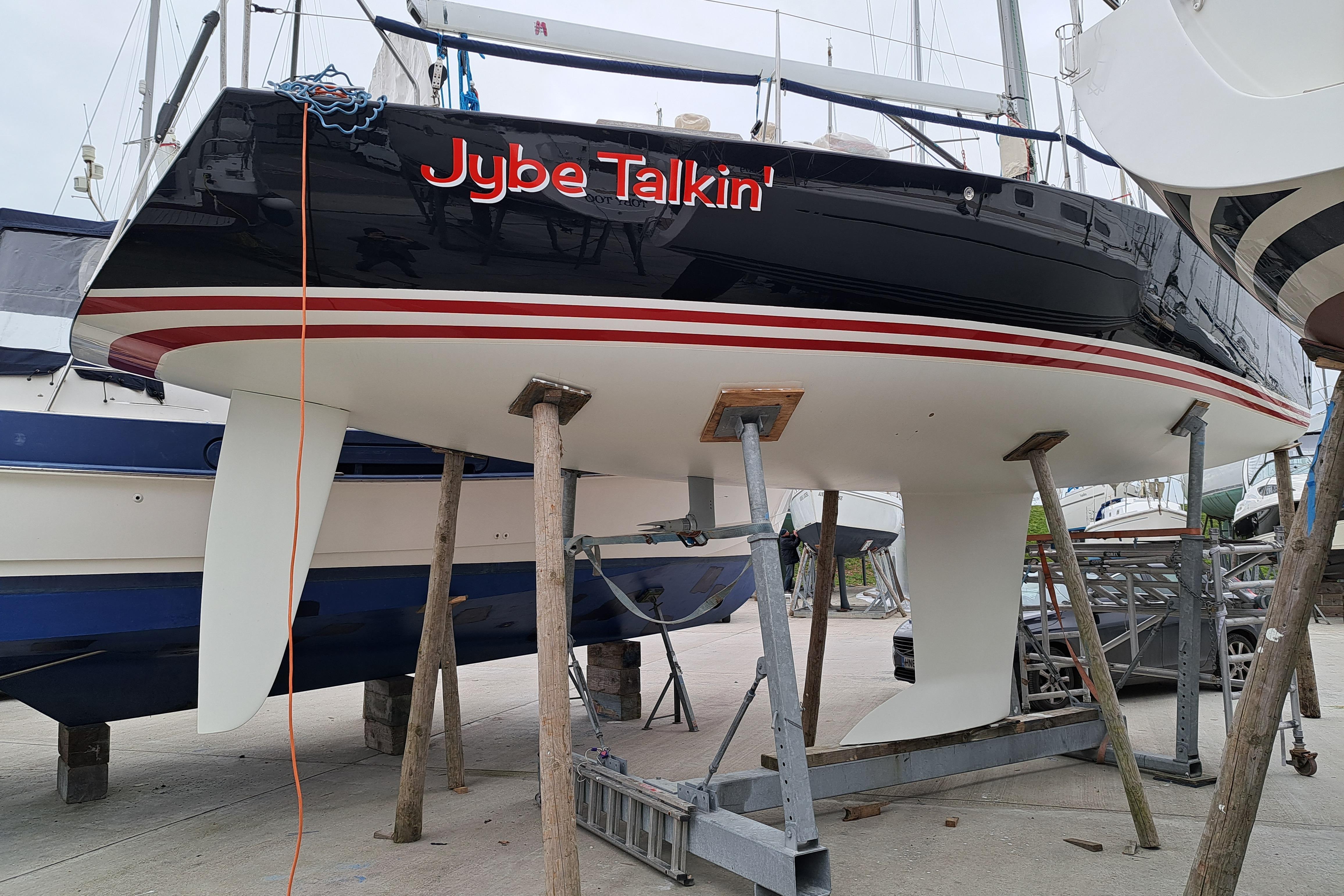 2004 J Boats J/109 sailboat "Jybe Talkin'" on stands in a boatyard.
