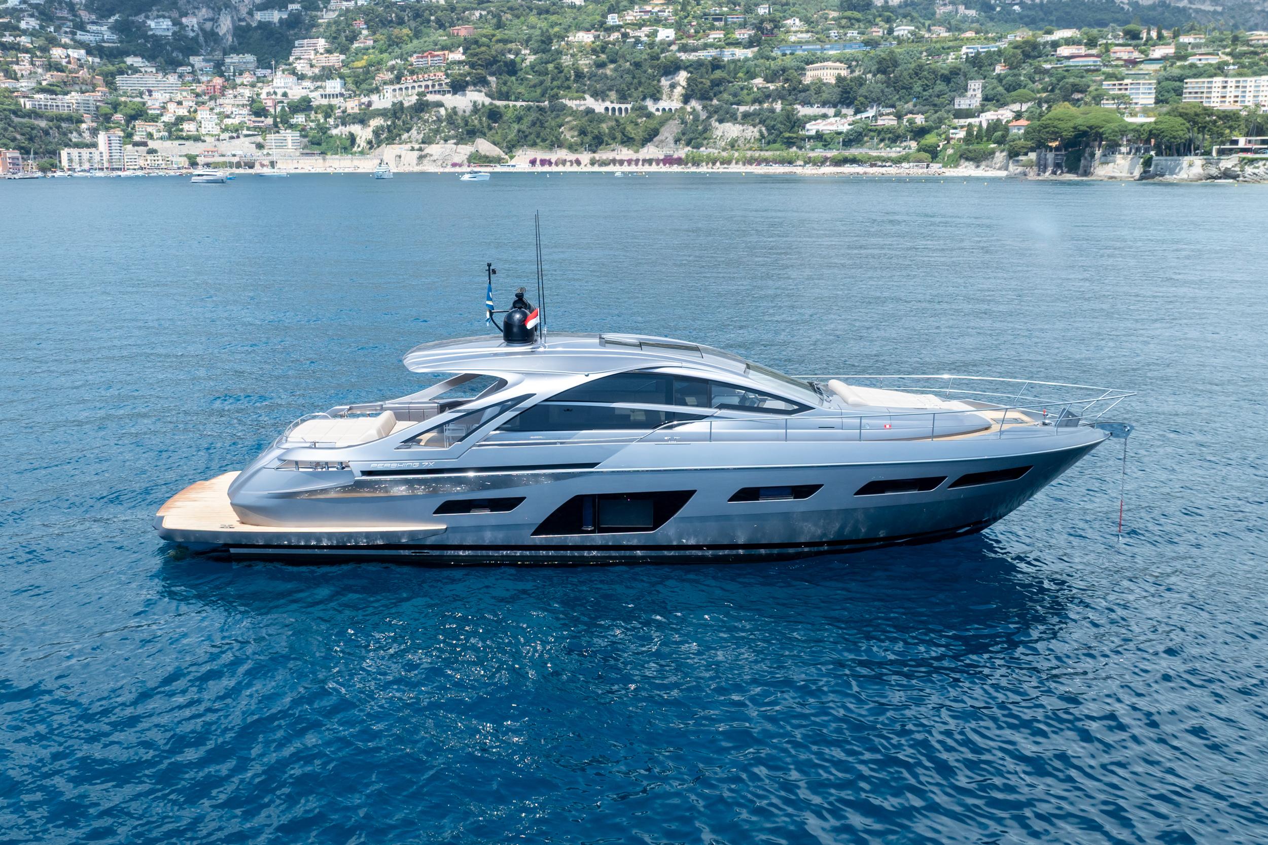 2024 Pershing 7X yacht cruising on clear blue waters near a scenic coastal town.
