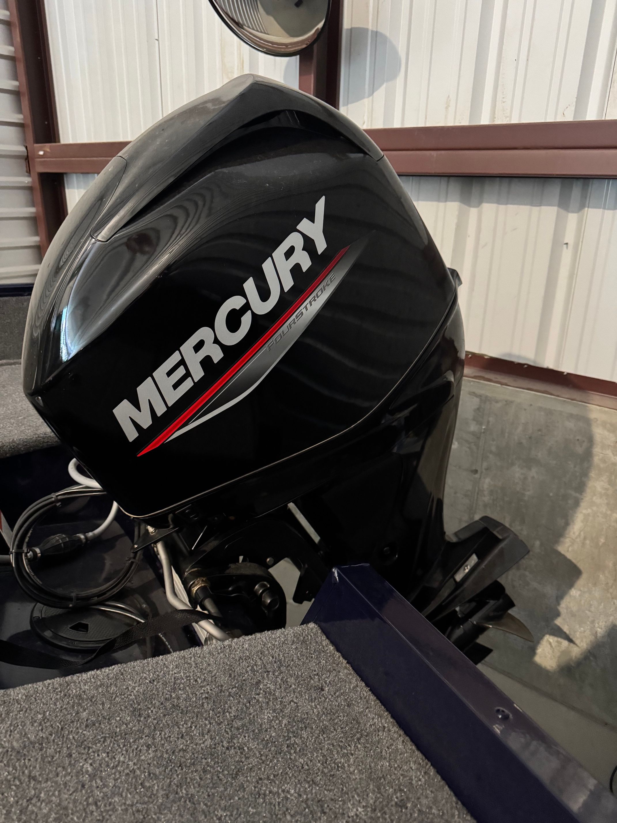 A Mercury outboard motor is mounted on a boat inside a warehouse.