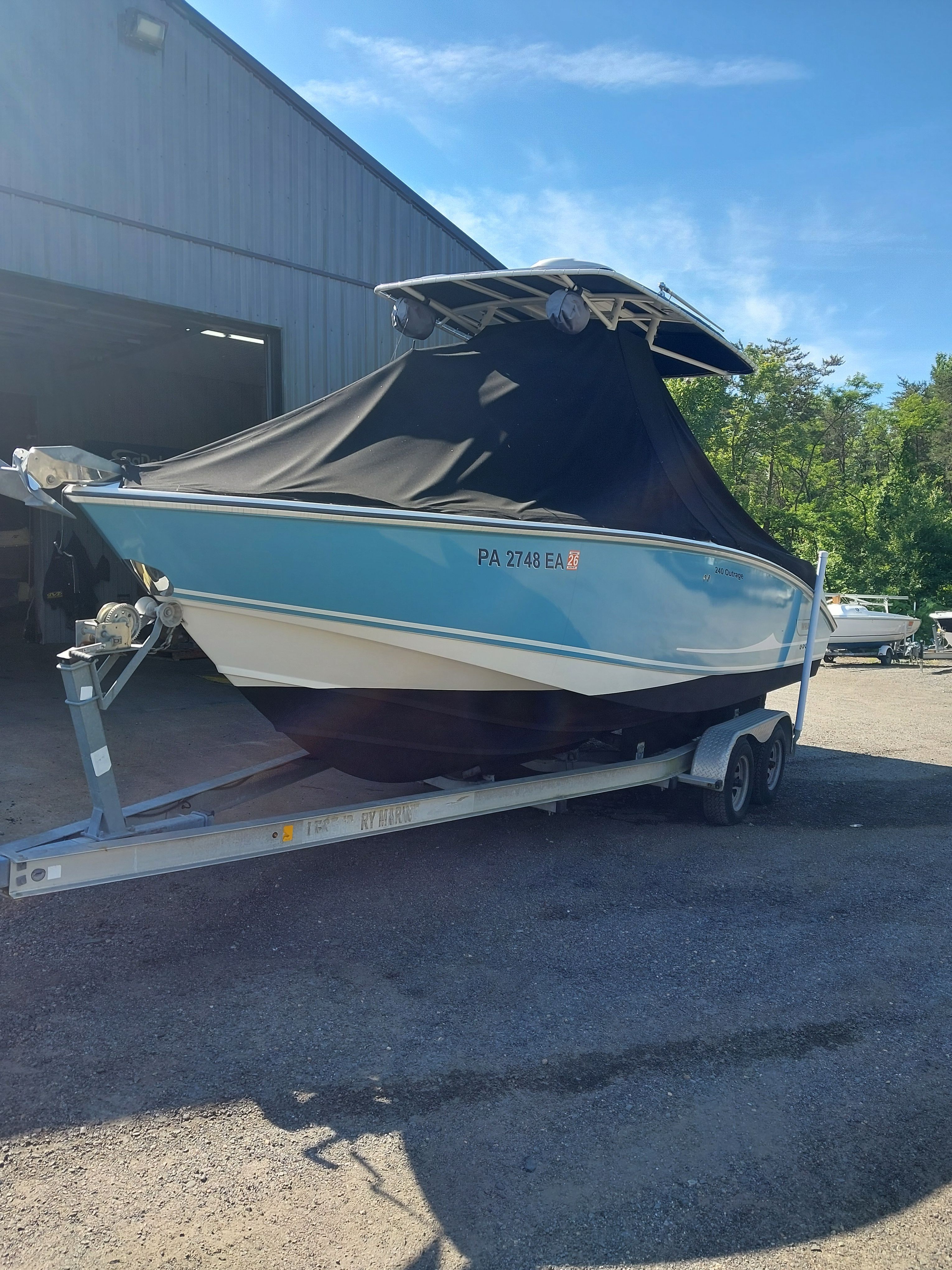 2005 Boston Whaler 240 Outrage on a trailer, partially covered.
