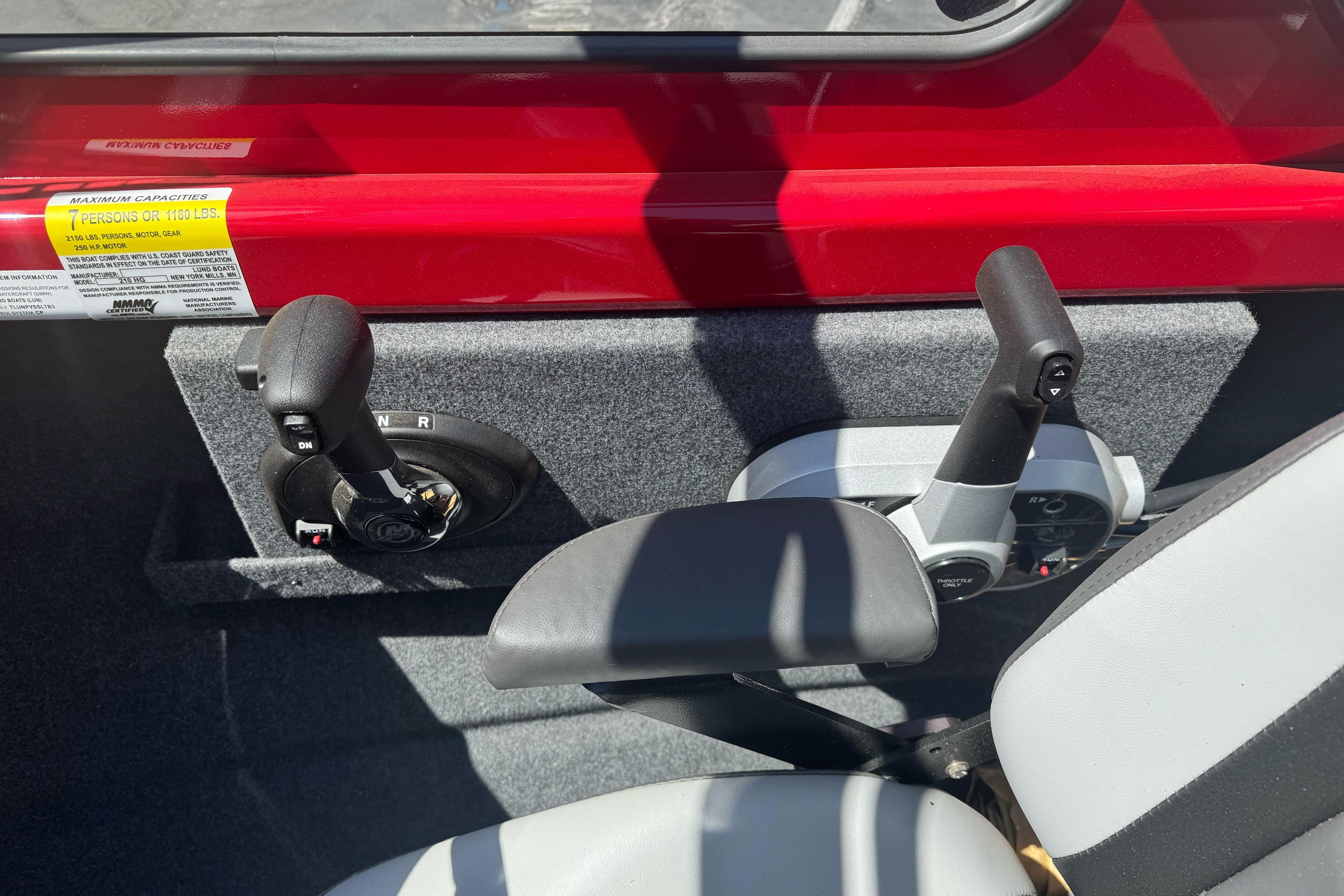 Interior controls of a 2026 Lund 210 Heavy Gauge boat, featuring dual levers and seating.