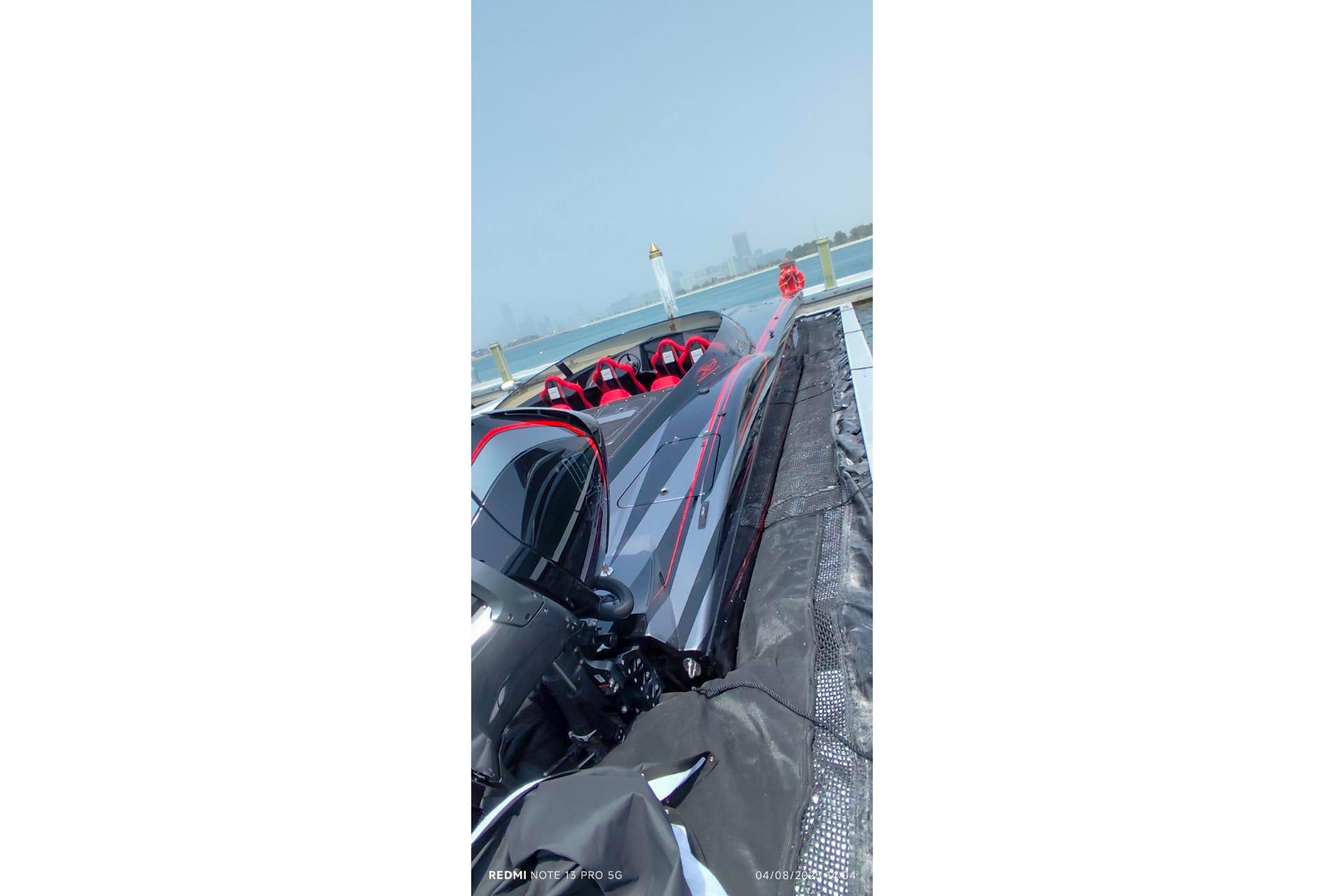 2025 MTI 440X speedboat docked, featuring sleek black and red design.