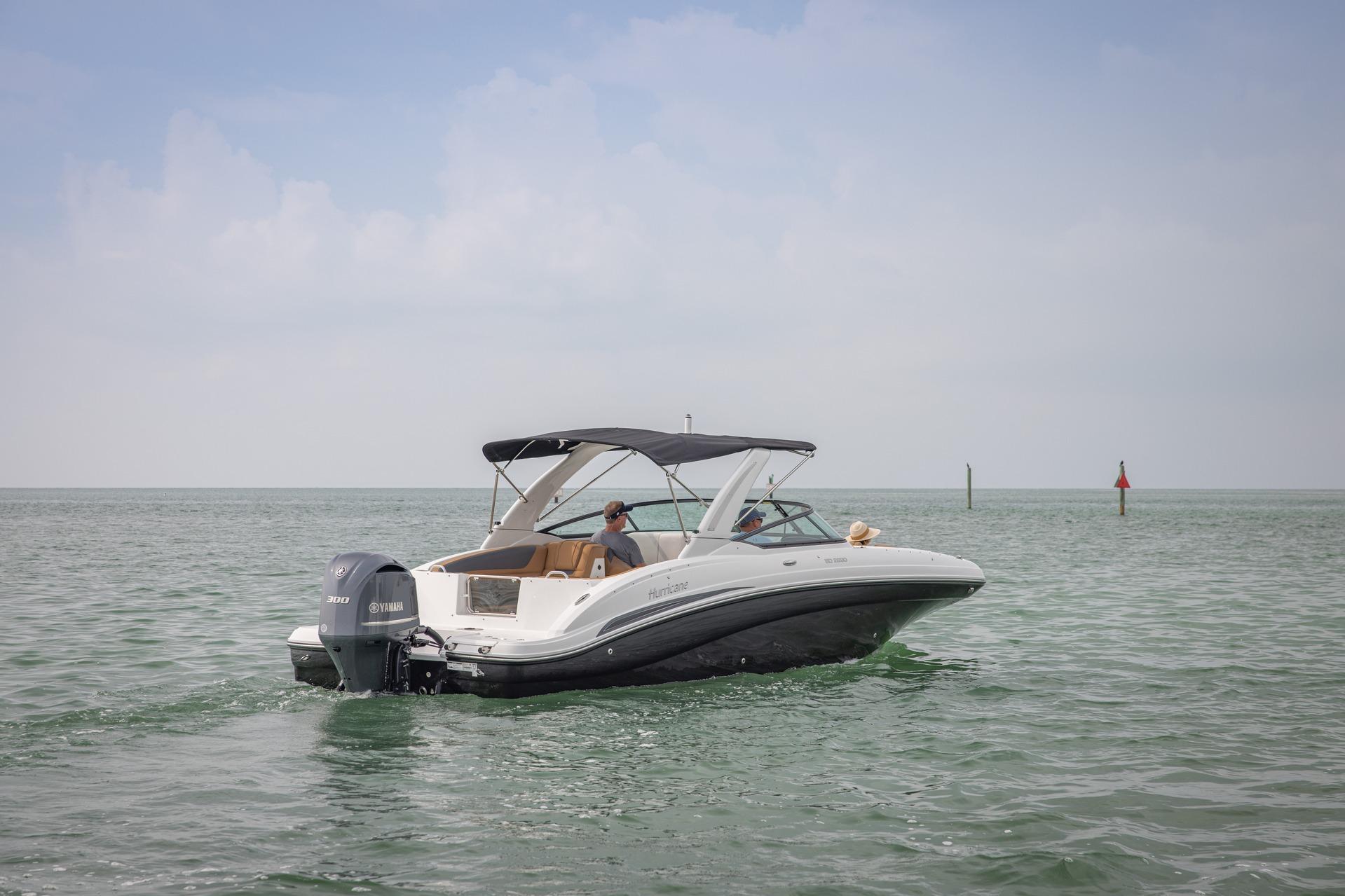 2026 Hurricane SunDeck 2690 OB boat cruising on calm waters under a clear sky.
