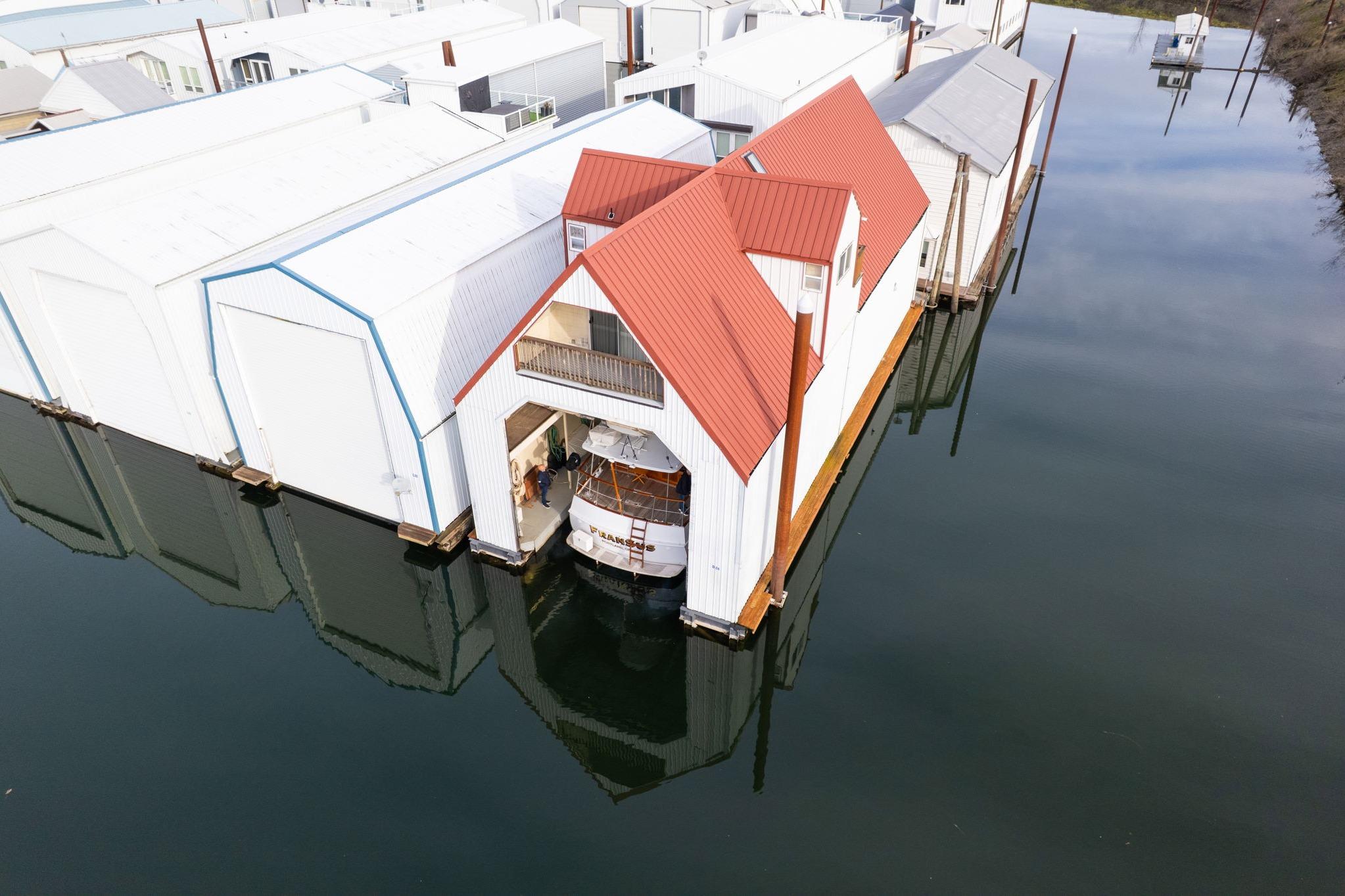 Aerial view of a 1976 custom boathouse with red roof on calm water.