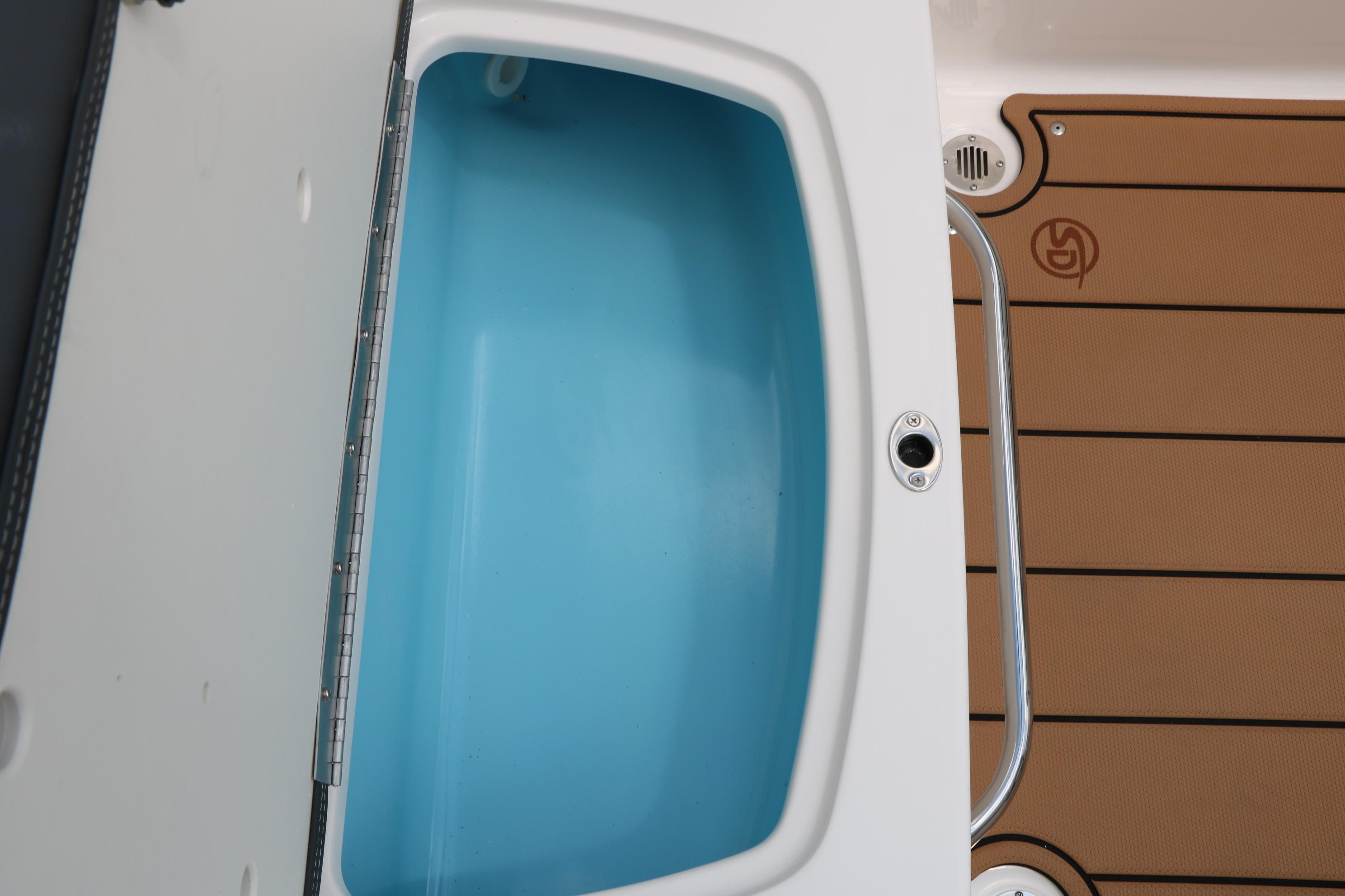 2025 Chaparral 23 SSi boat interior with open storage compartment and teak-style flooring.