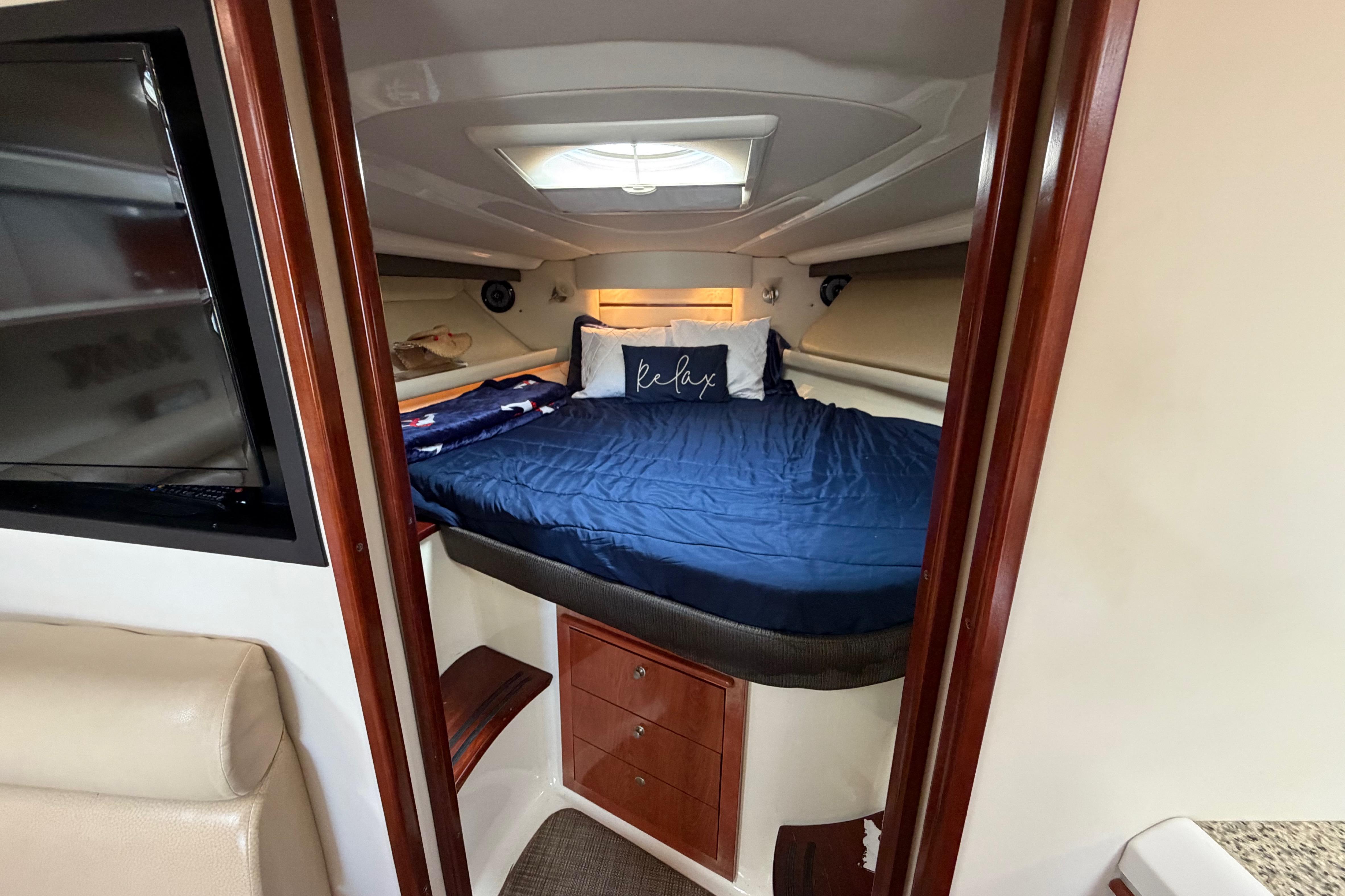 Cozy cabin interior of 2007 Monterey 350 Sport Yacht with blue bedding and TV.