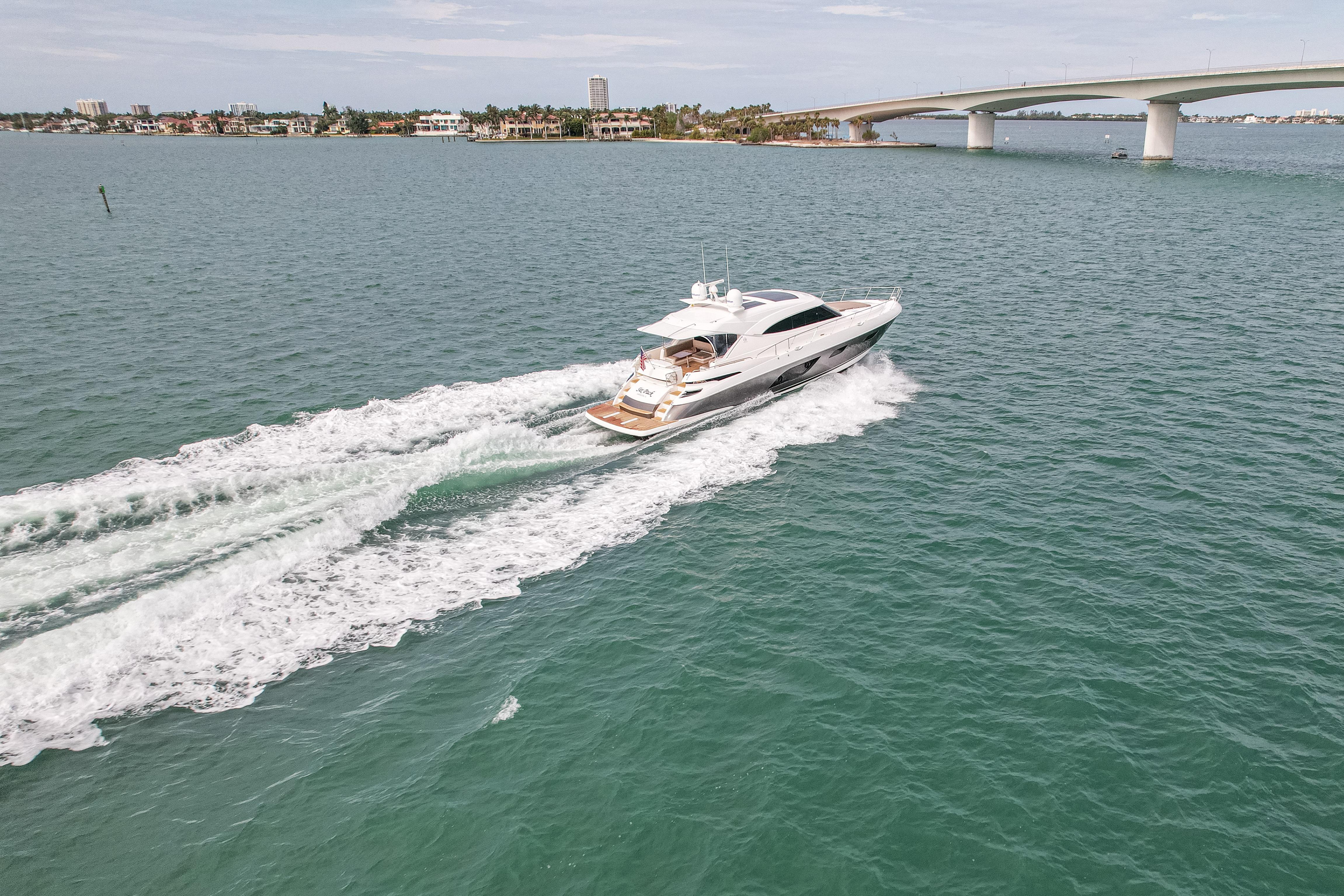 2015 Riviera 6000 Sport Yacht cruising on open water near a bridge.