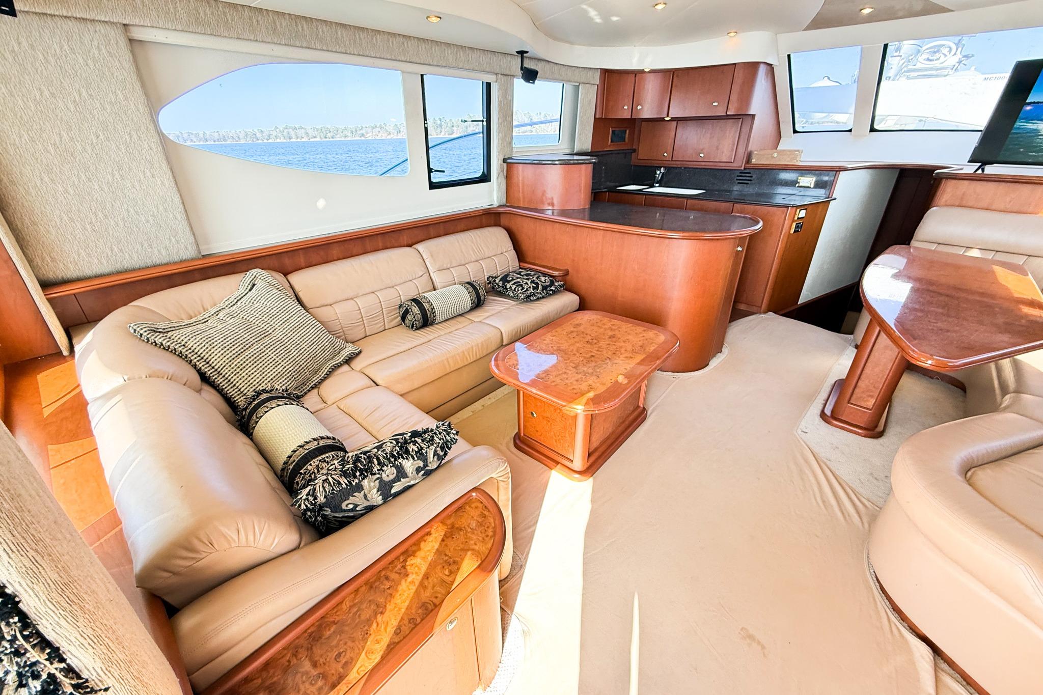 Luxurious interior of a 2004 Silverton 48 Convertible yacht with plush seating and elegant wood finishes.