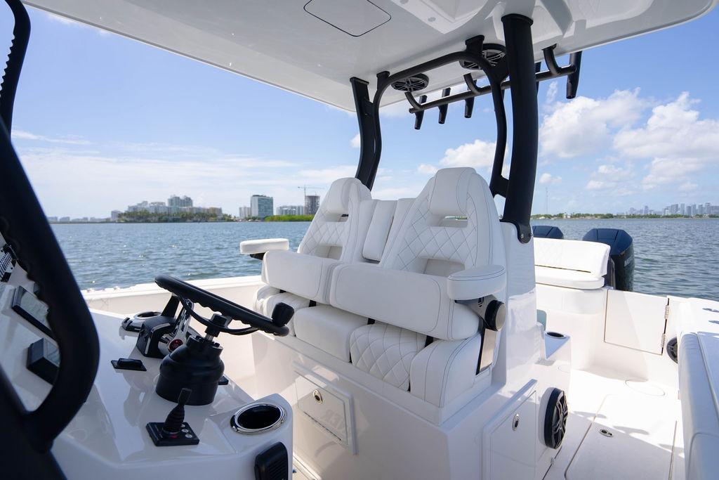 Luxury interior of 2027 Reef Runner 340 boat with white seating and steering wheel.