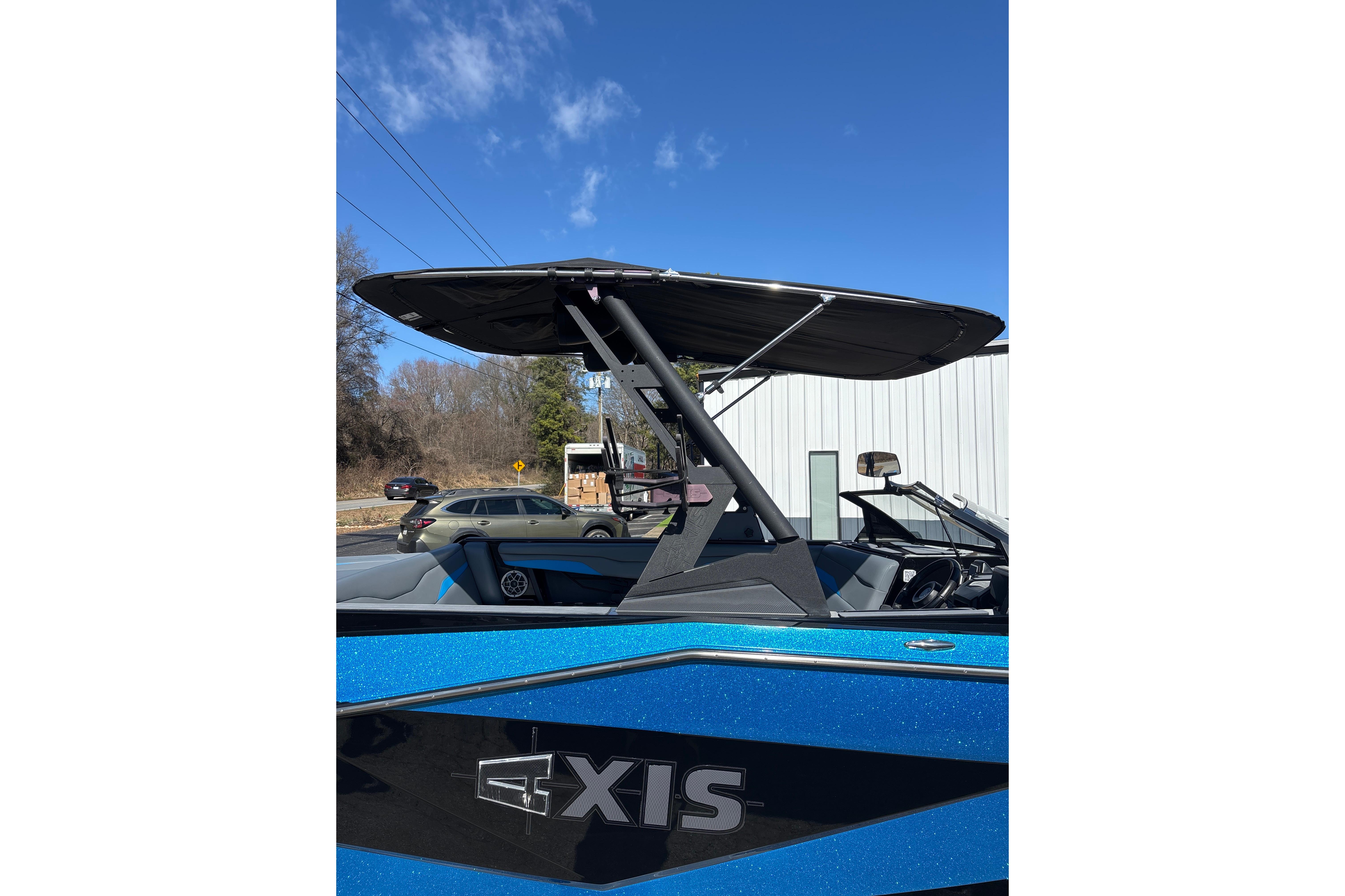 2023 Axis T220 boat with blue exterior and black canopy under clear sky.