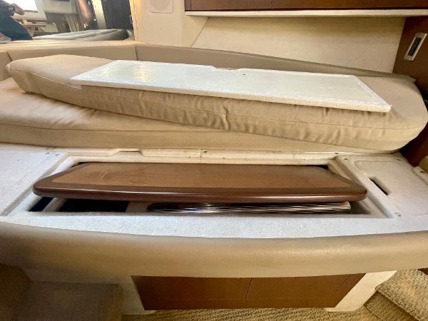 2014 Sea Ray 330 Sundancer interior storage compartment with beige cushions and wooden panel.