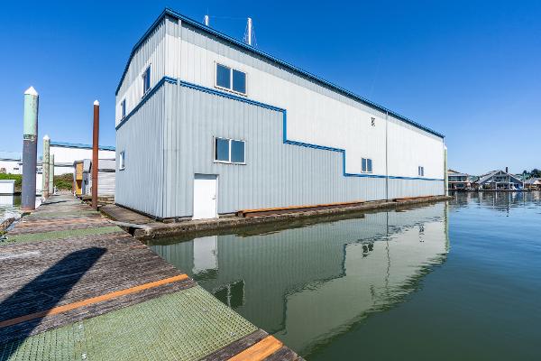 Large 1985 Custom Larson Boathouse on calm water, clear blue sky background.
