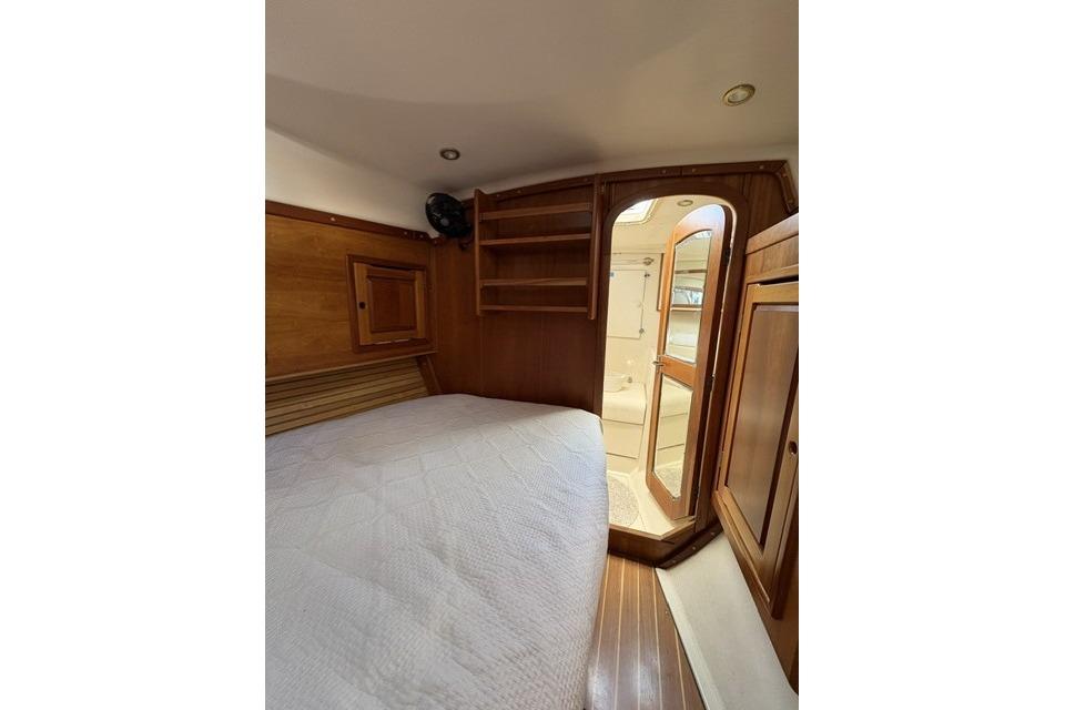 Cozy cabin interior of 2002 Saga 43 yacht with wooden furnishings and bed.