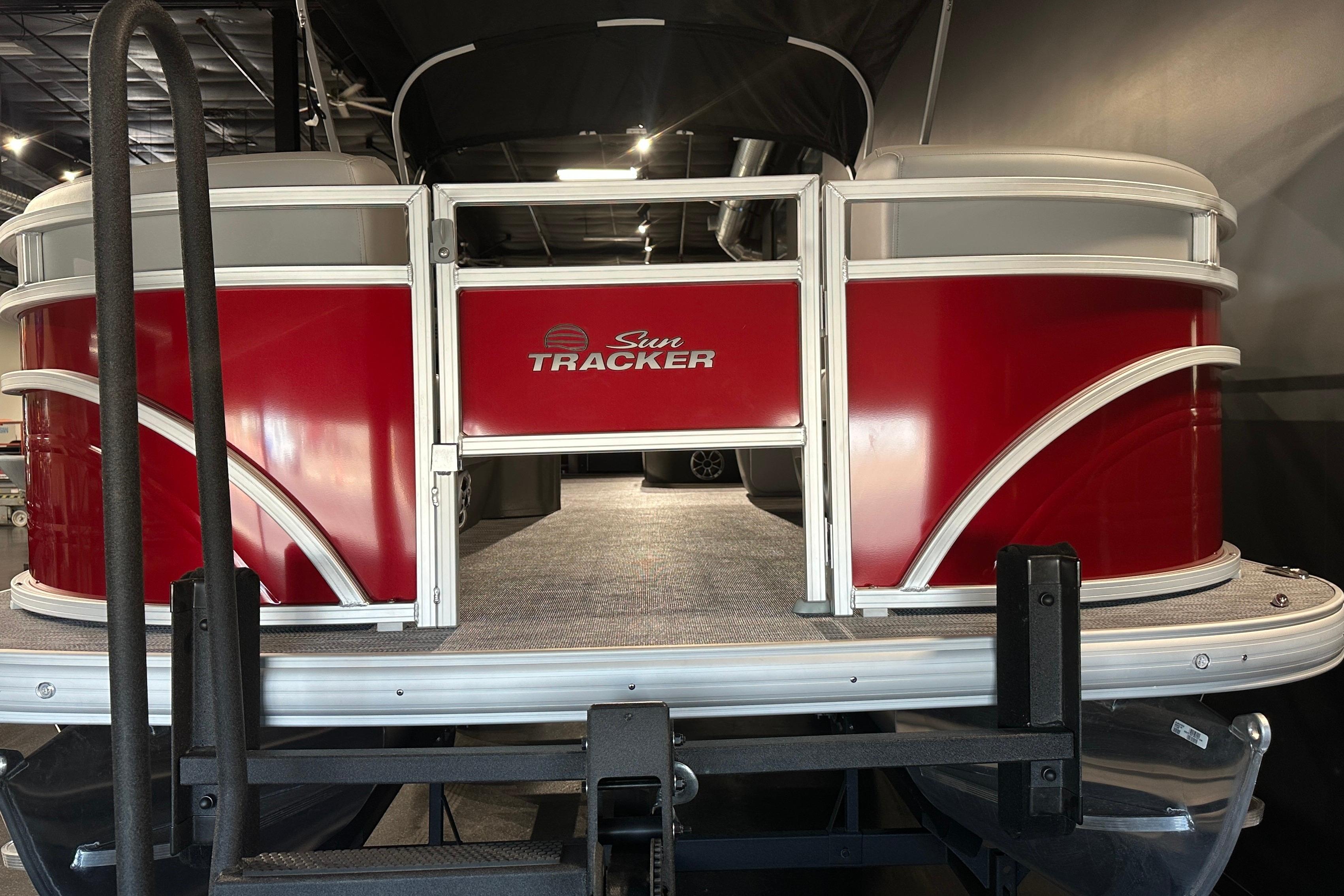 2026 Sun Tracker SportFish 22 DLX pontoon boat with red exterior in showroom.