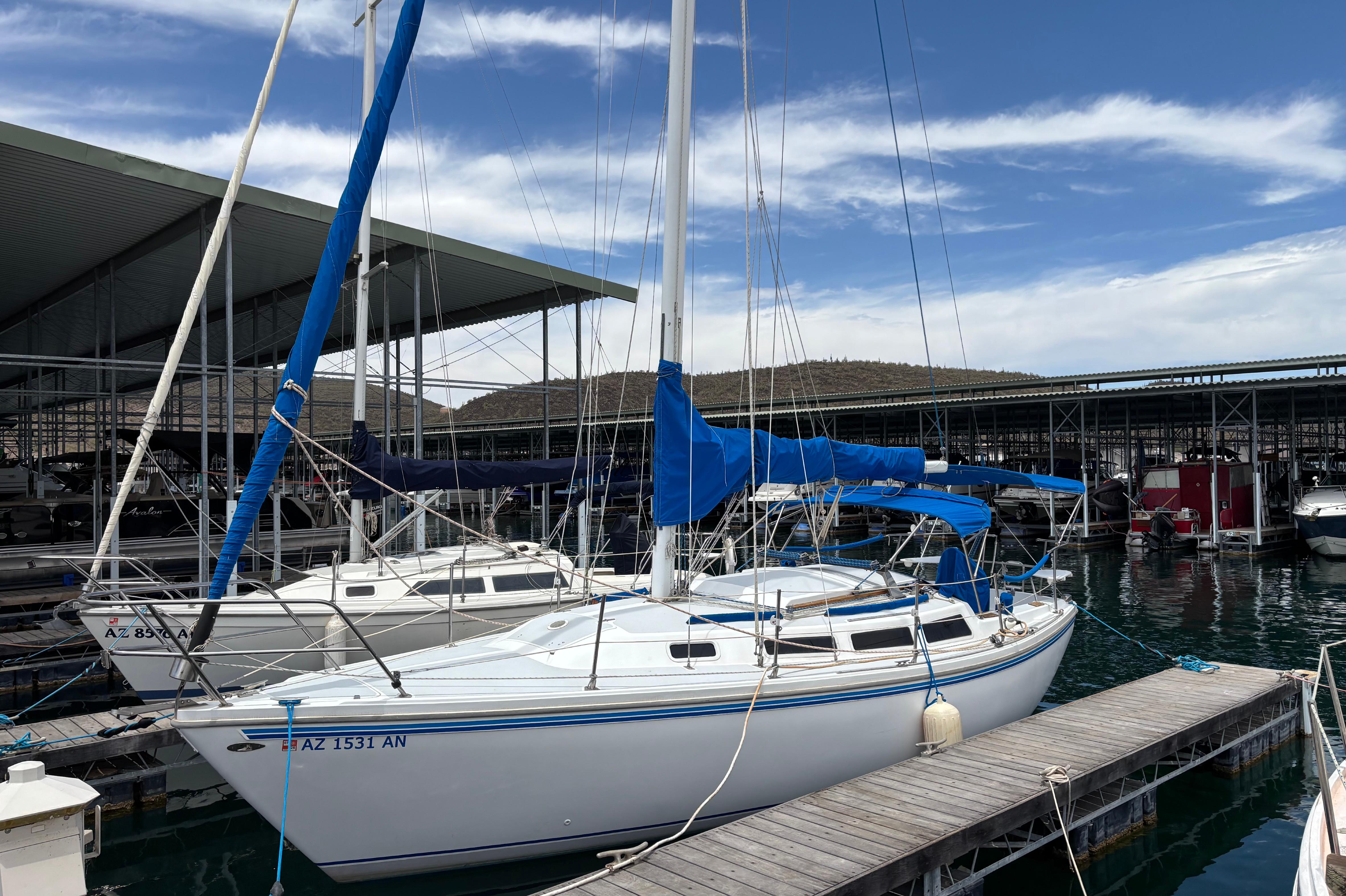 1980 Catalina 30 sailboat docked at marina under blue sky.