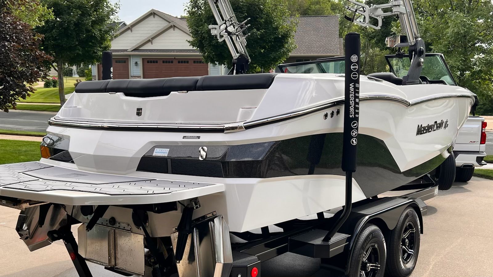 A white 2020 MasterCraft NXT22 boat on a trailer in a residential area.