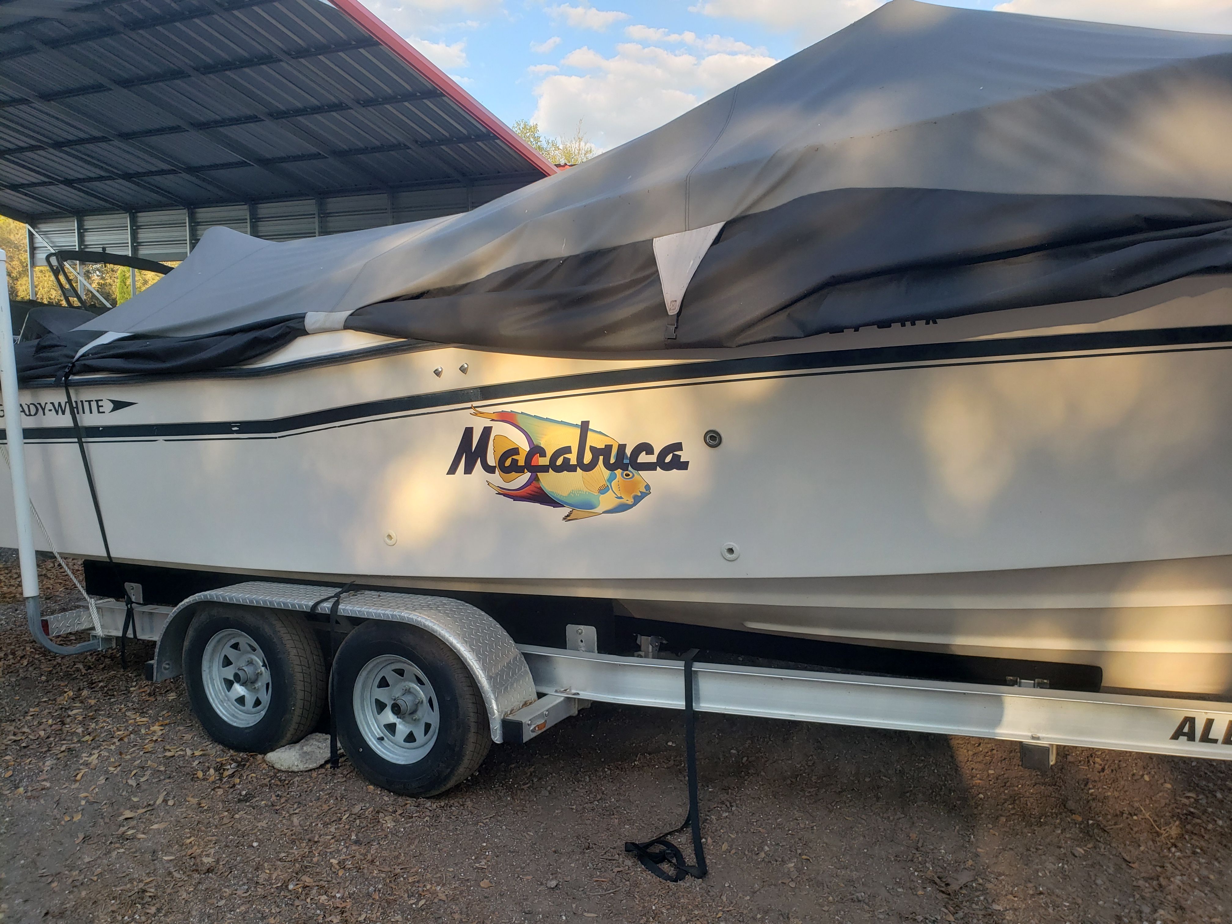 A 1995 Grady-White Explorer 24 boat on a trailer, partially covered with a tarp.