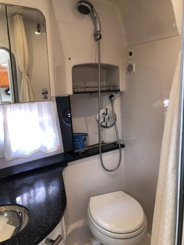 Interior view of a boat bathroom with toilet, sink, and shower.