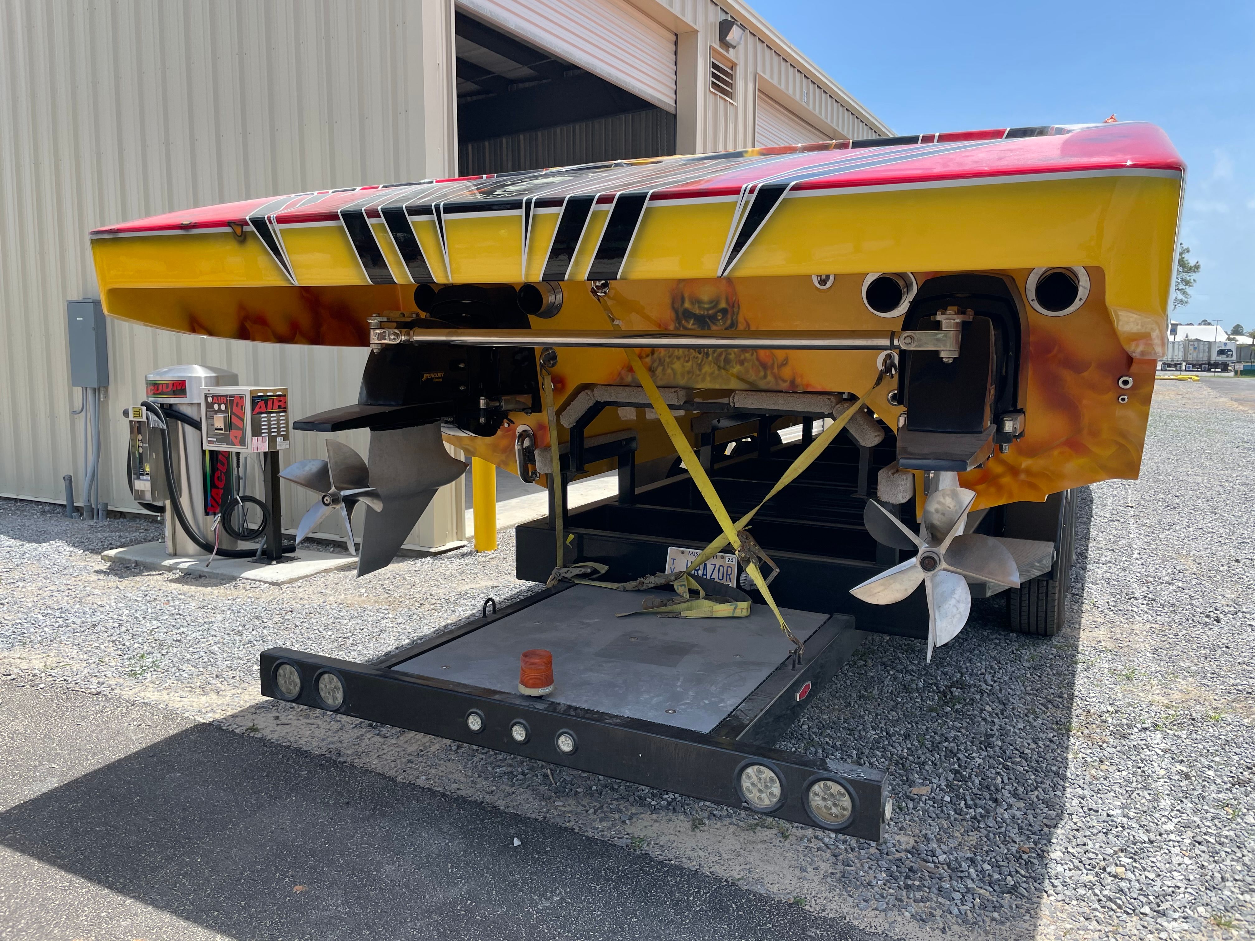 A 2010 MTI CAT with a bright yellow and red stern, two large propellers, and a trailer.