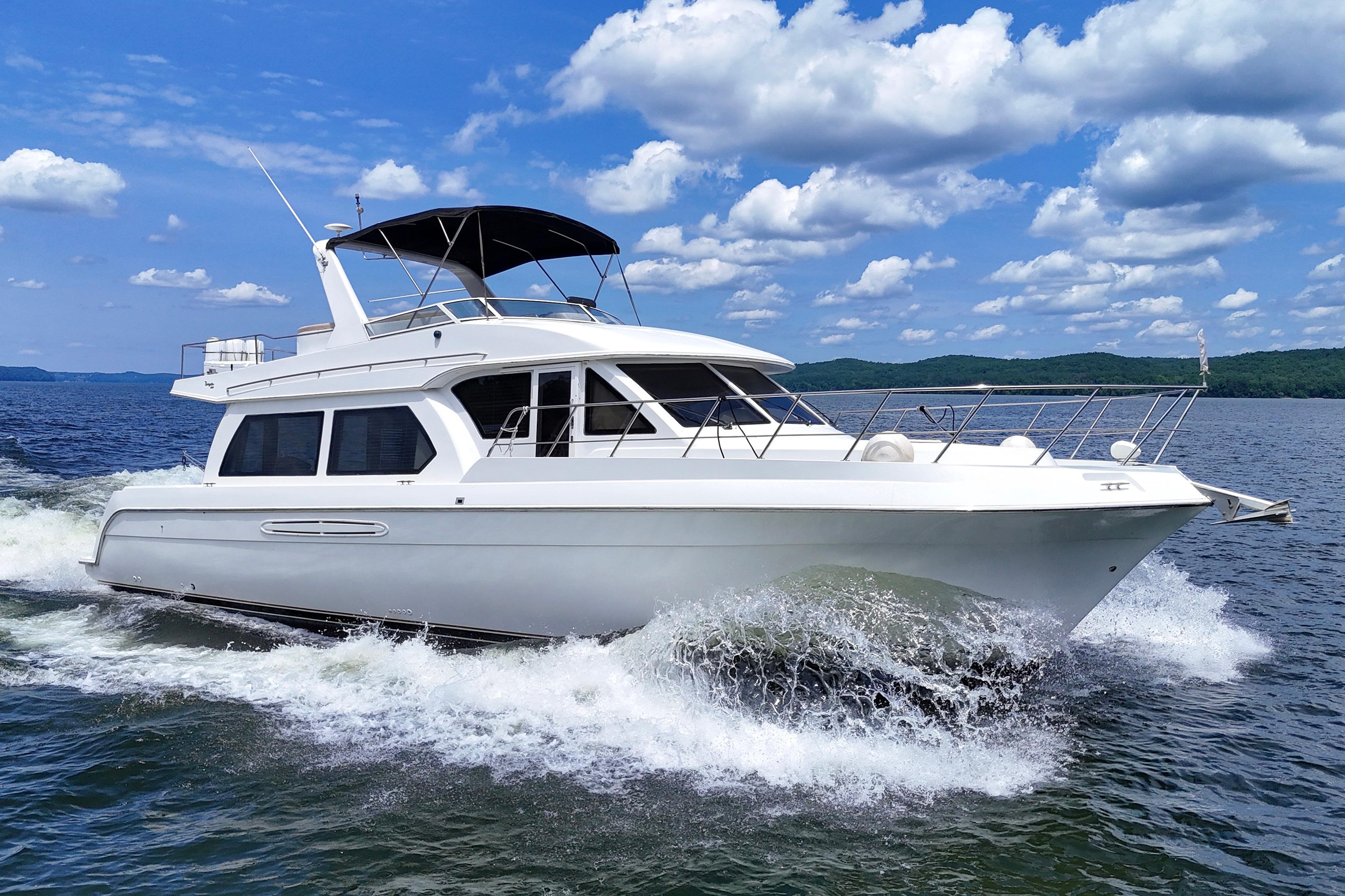 2007 Navigator 5100 yacht cruising on a lake under a blue sky with clouds.