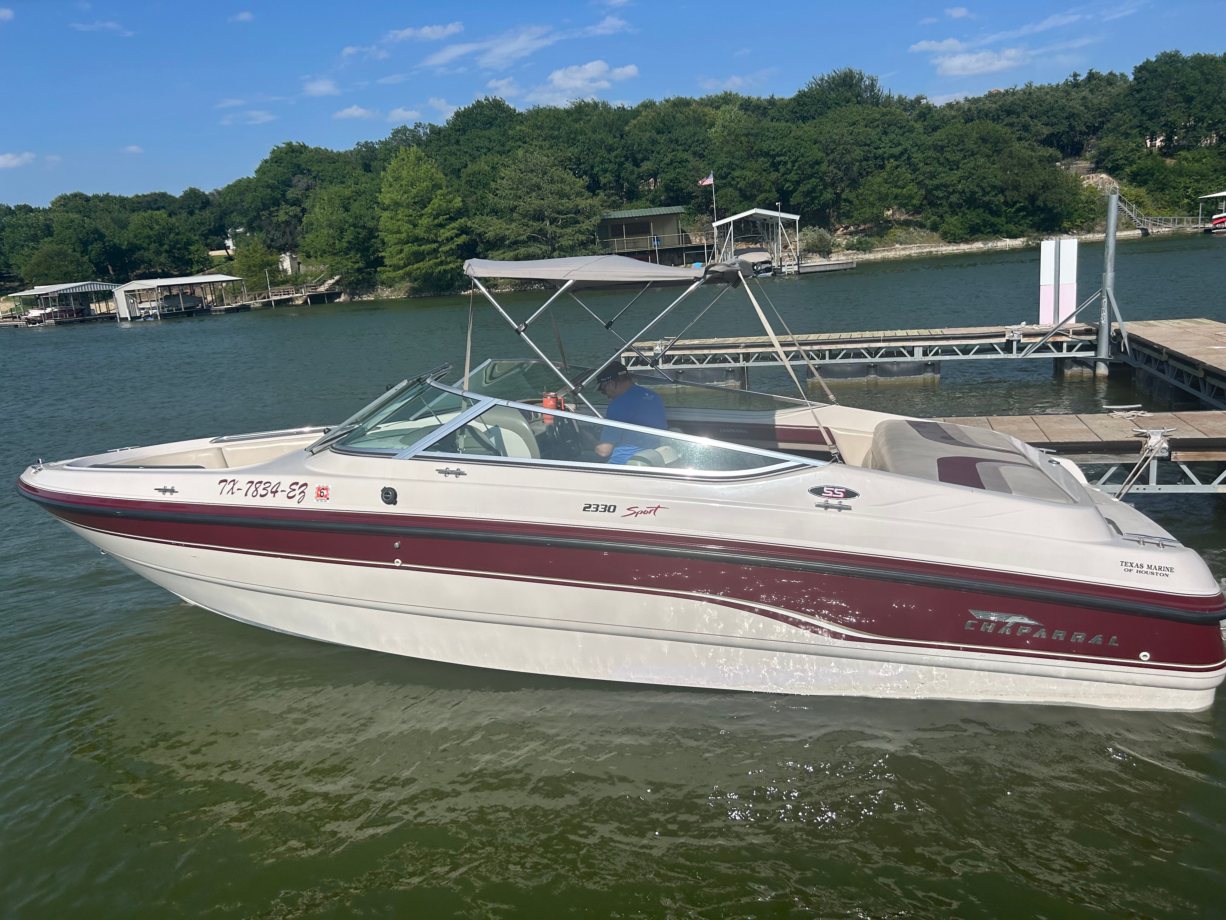 A 1995 Chaparral 2330 boat docked on a calm lake.