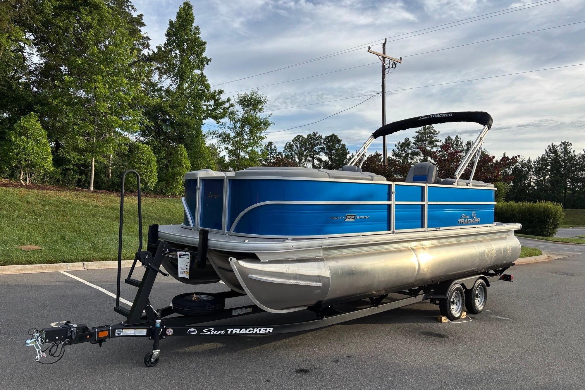 2026 Sun Tracker Party Barge 22 XP3 pontoon boat on trailer in a parking lot.