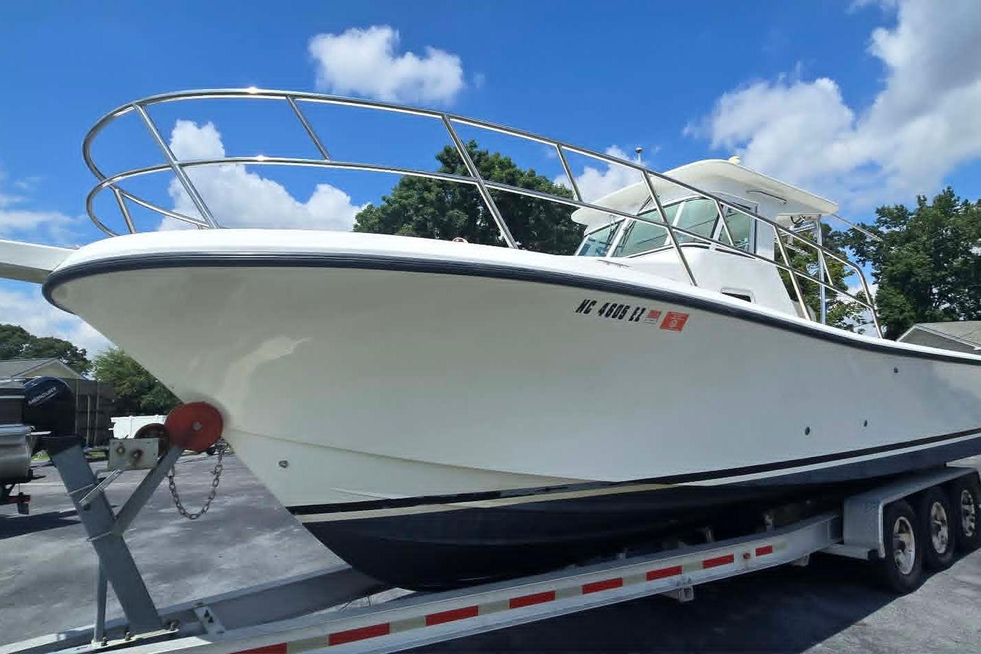 2003 True World Marine 286 boat on trailer under clear blue sky.