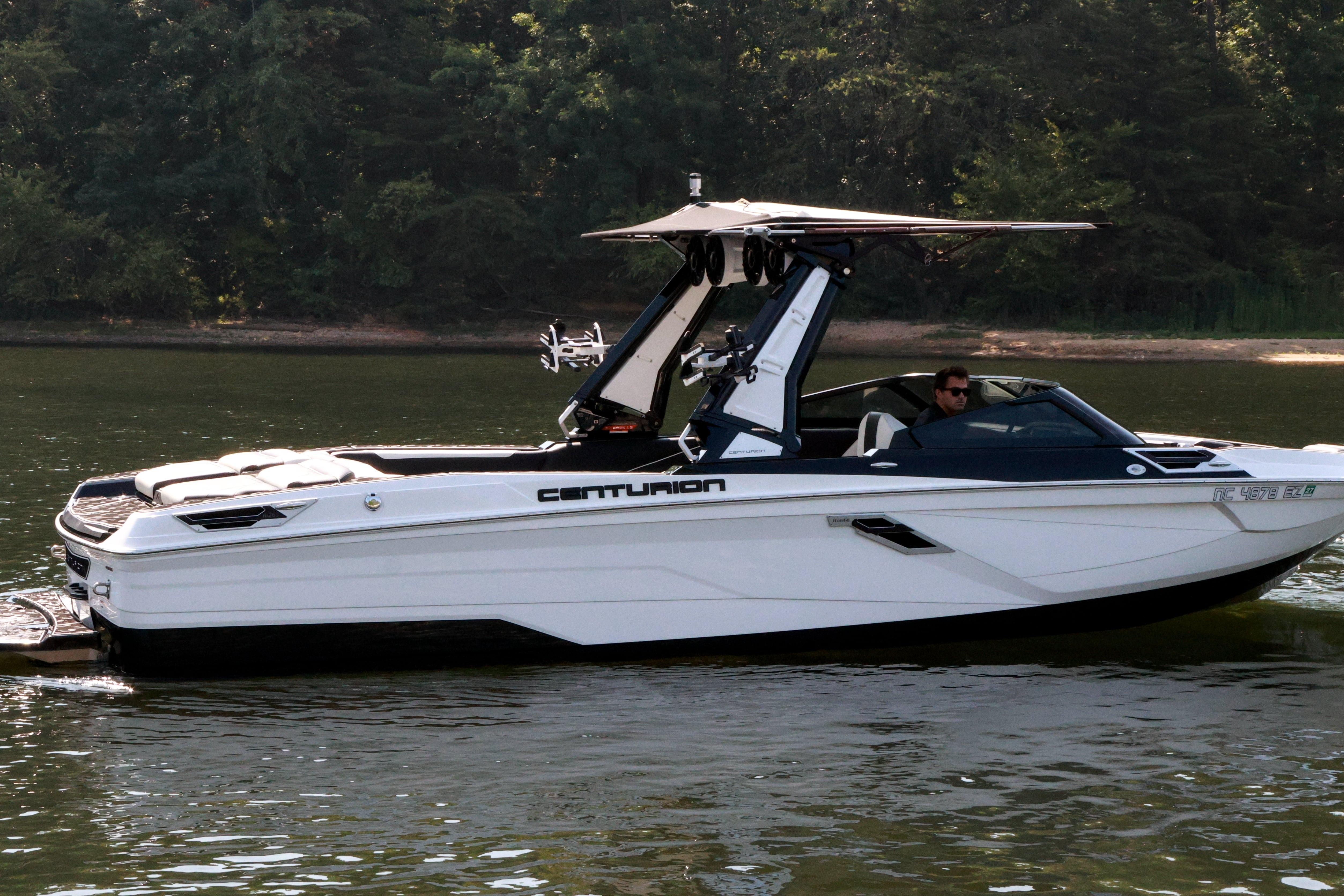 2022 Centurion Ri265 boat cruising on a calm lake with lush forest backdrop.