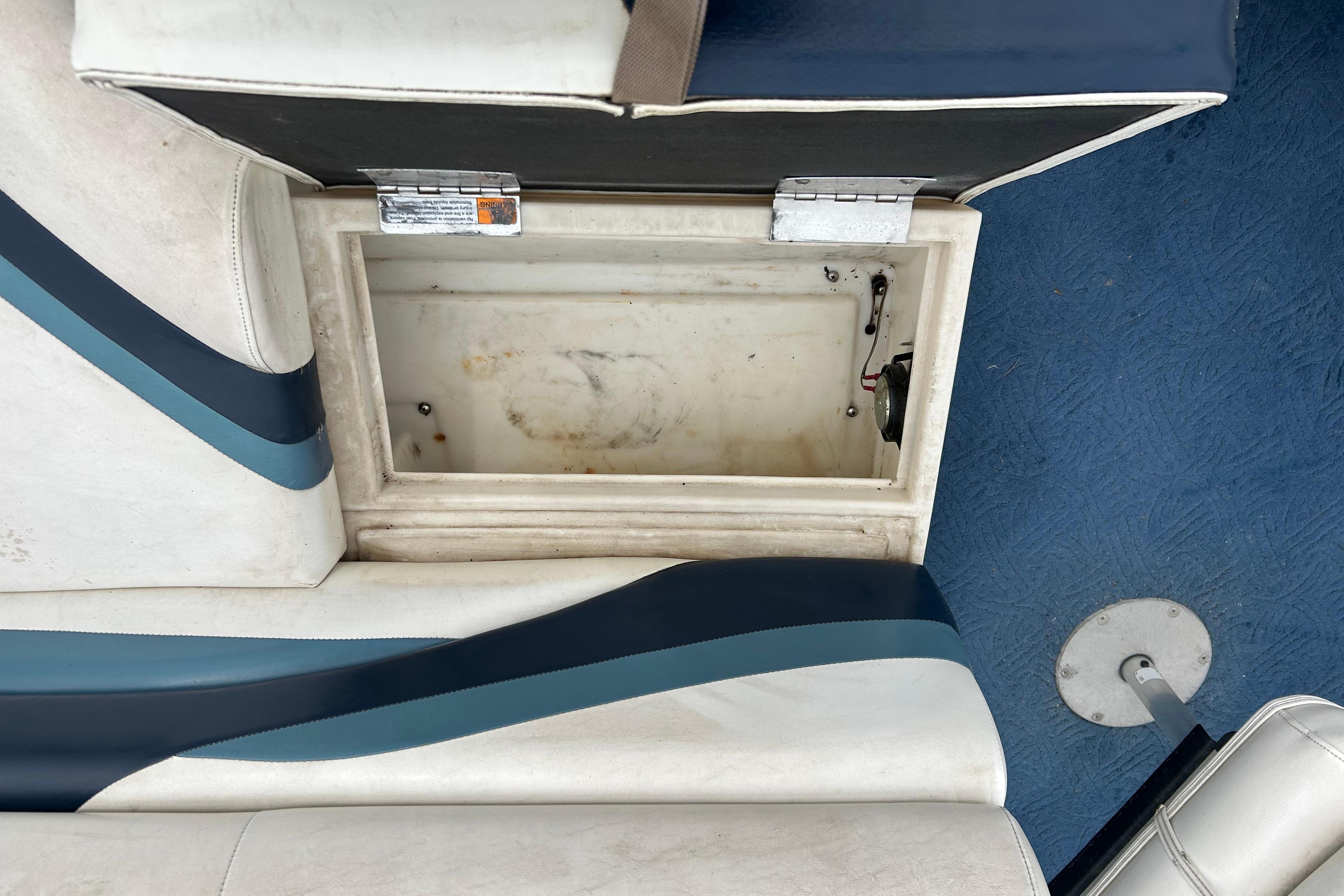 Open storage compartment on a 2002 Lowe Trinidad 200 boat with blue and white seating.