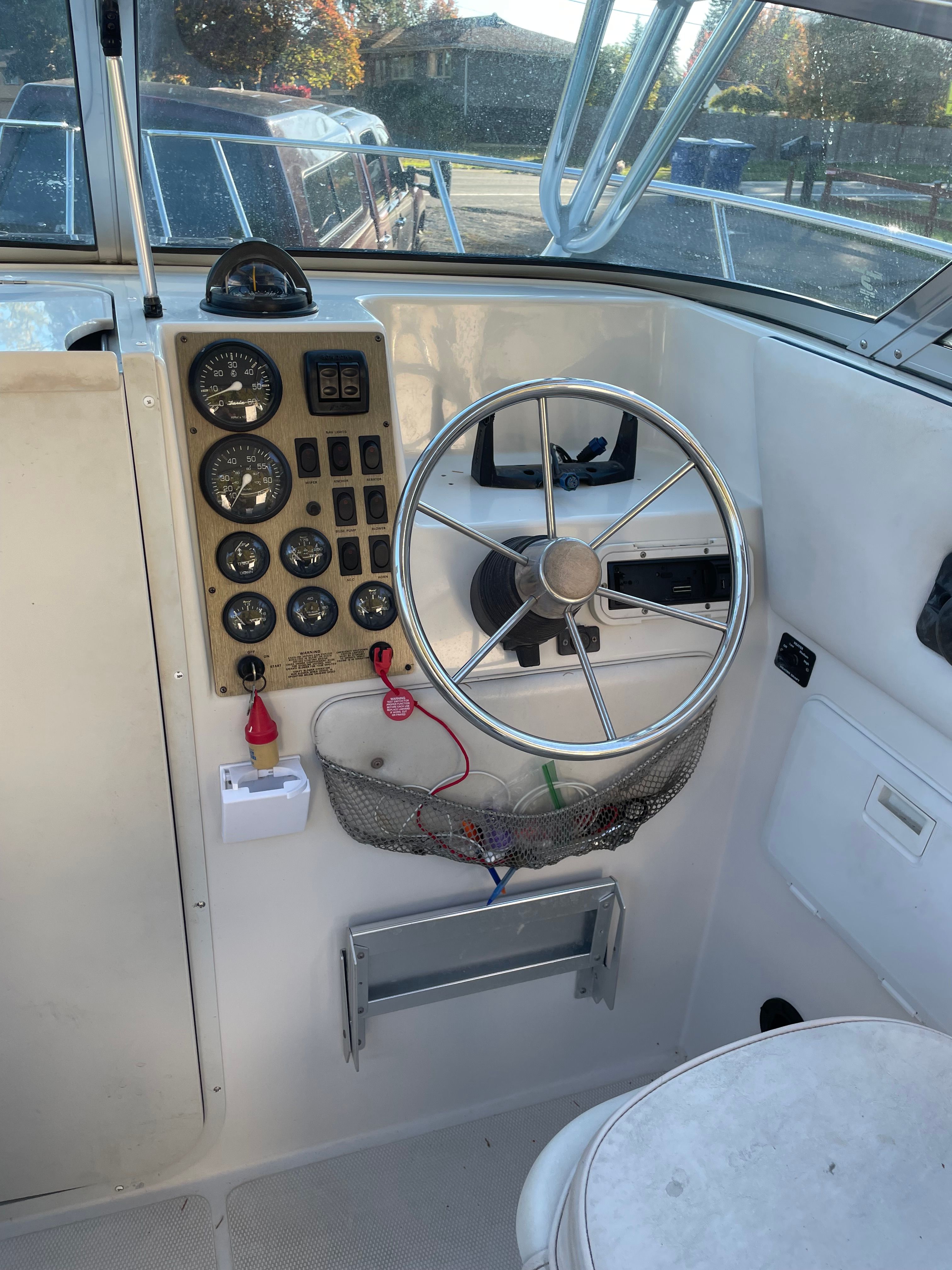 The image shows the helm of a 2001 Bluewater 2100 Sport Fisher. There's a steering wheel, instruments, and a mesh pocket.