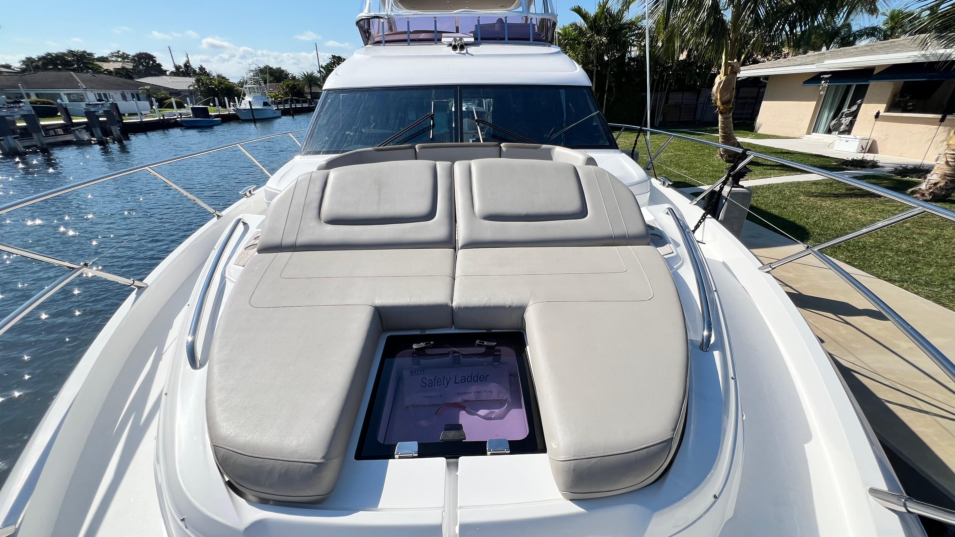 Luxurious 2019 Princess F62 yacht with sunbathing deck, docked in a scenic marina.