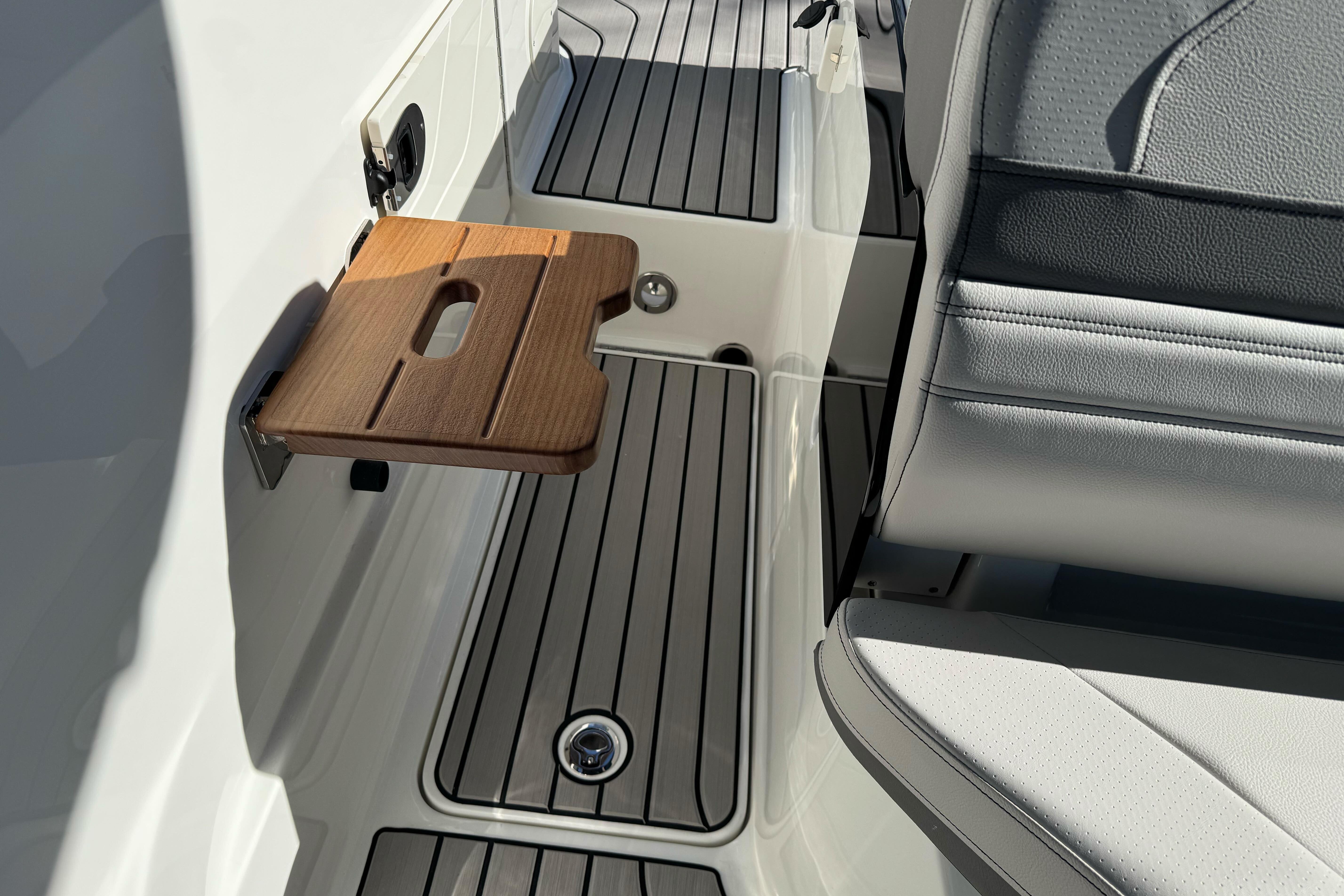 2026 Sea Ray SLX 260 boat interior with wooden fold-out table and sleek seating.