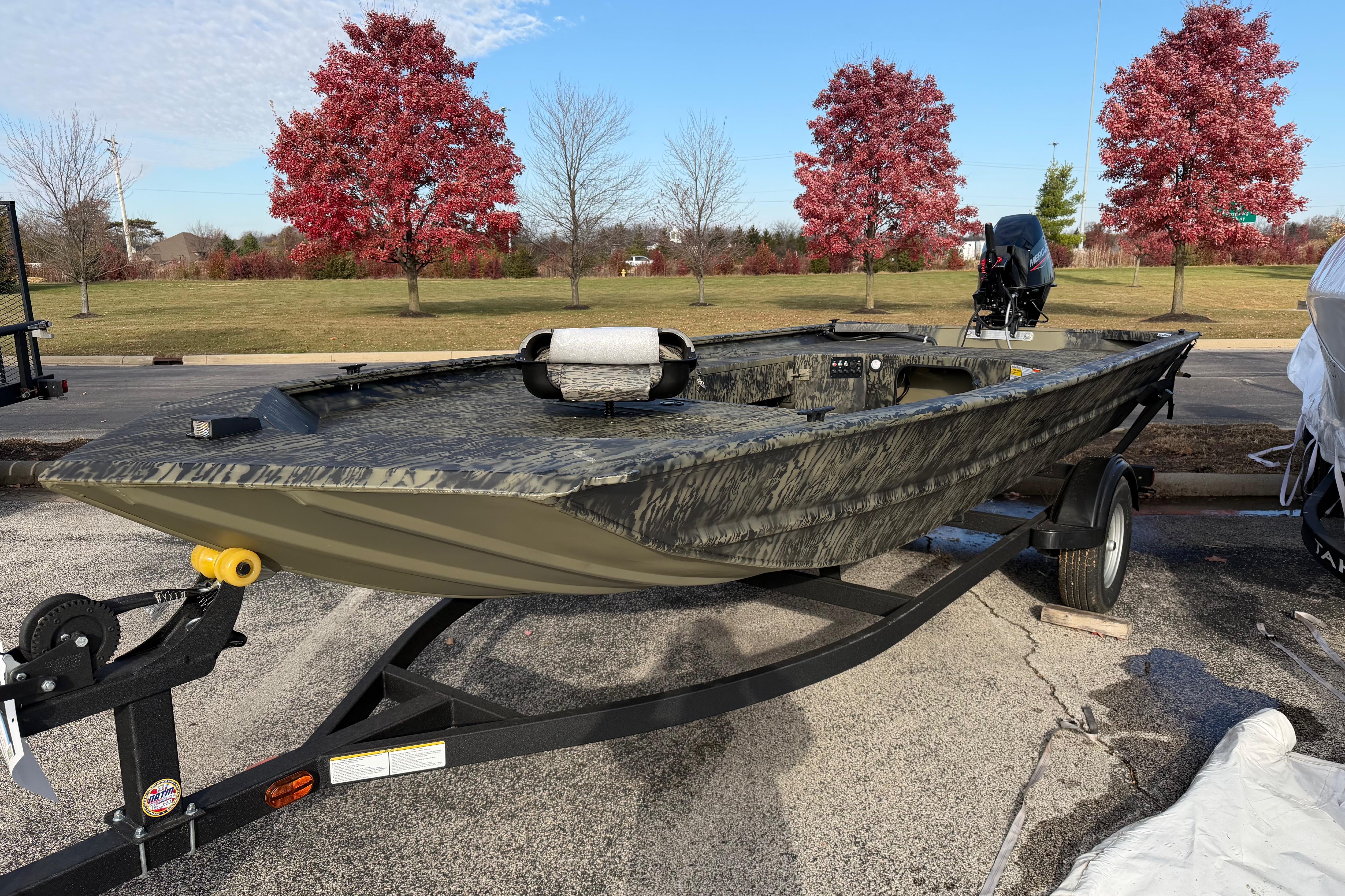 2026 Tracker Grizzly 1654 T Sportsman boat on trailer, parked outdoors with autumn trees.