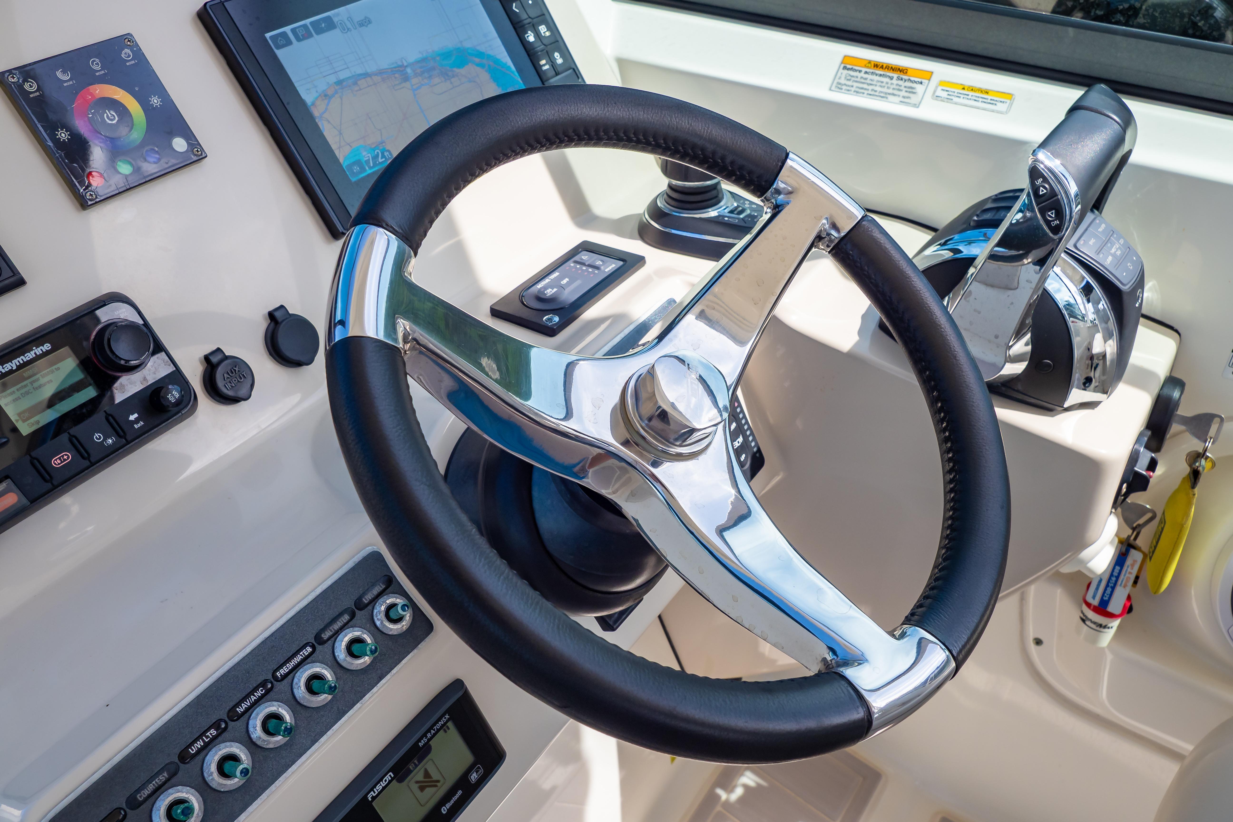 Steering wheel and controls of a 2019 Boston Whaler 270 Vantage boat cockpit.