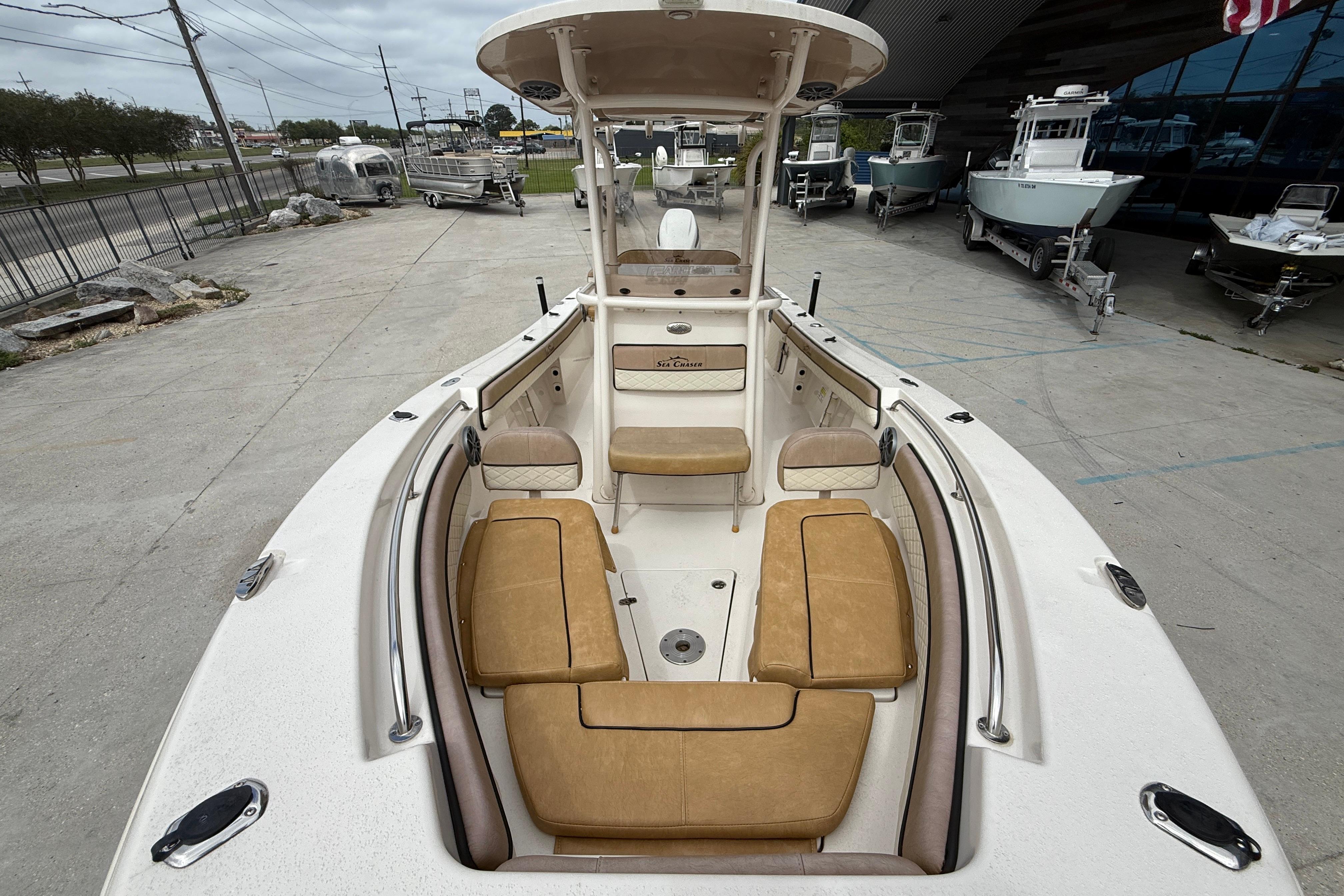 2023 SeaChaser 24 HFC boat with tan seating, displayed outdoors at a dealership.