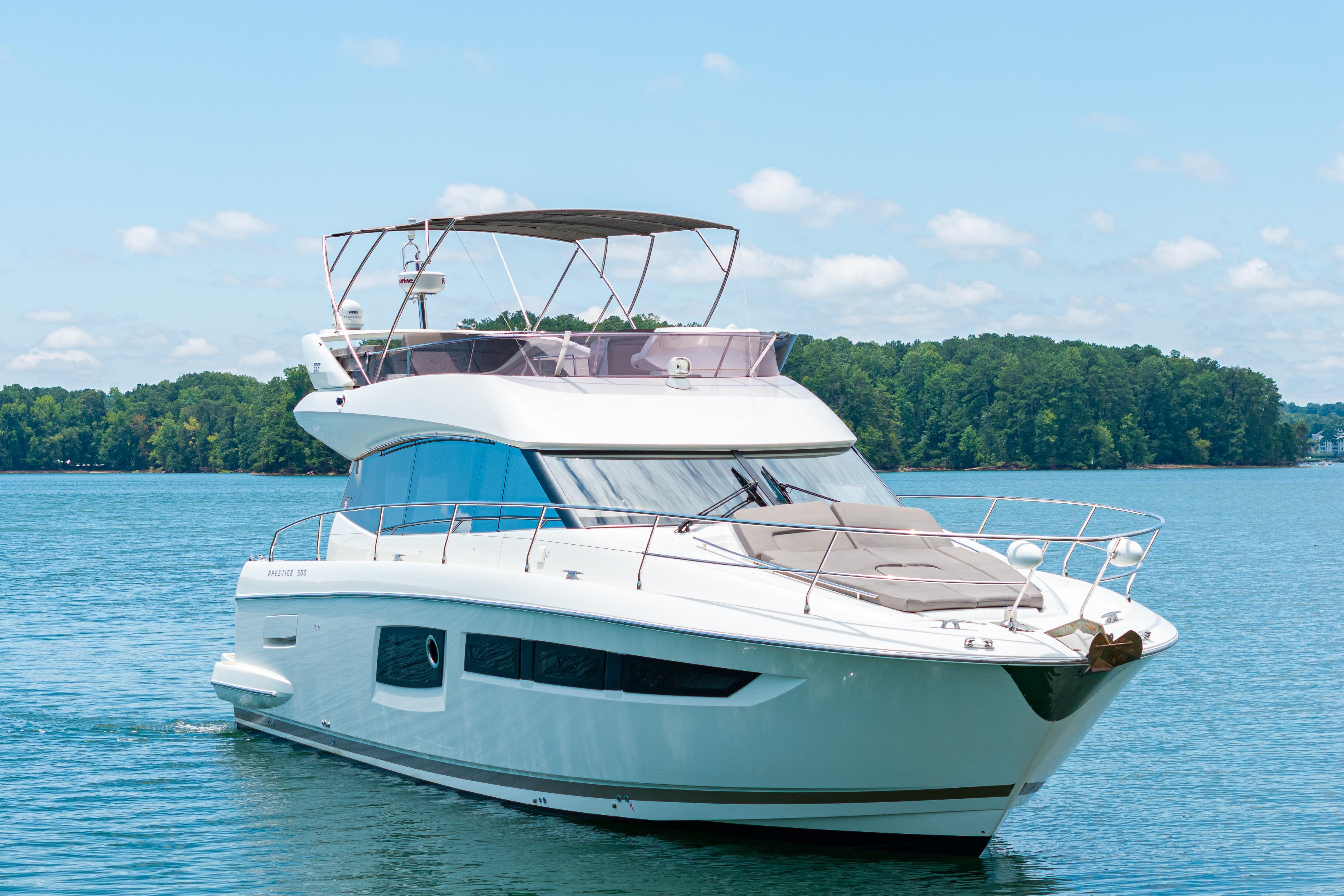 Luxury 2017 Prestige 500 yacht cruising on a serene lake with lush green shoreline.