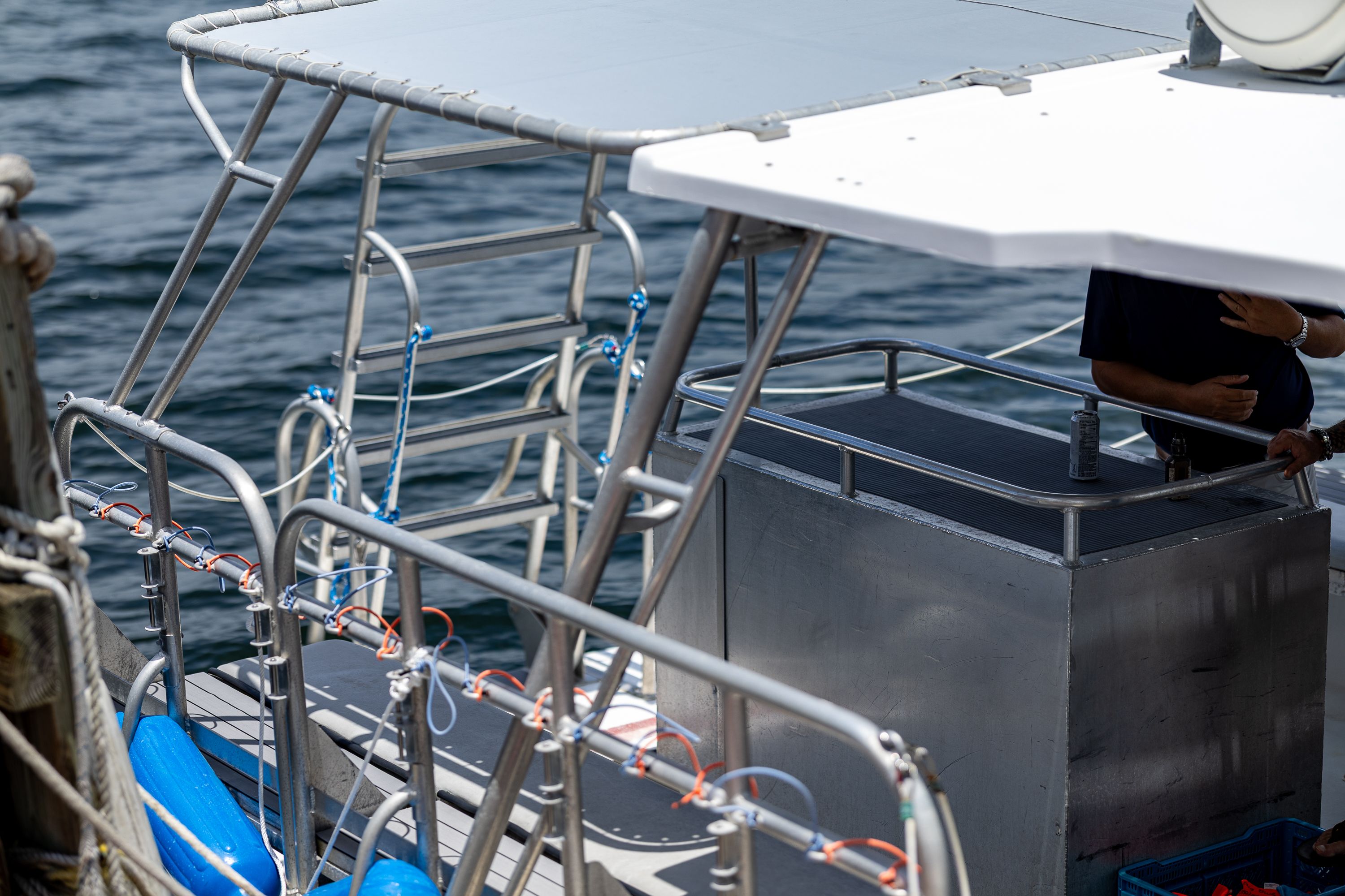 A dive boat with metal railings and blue life vests, docked at a pier.