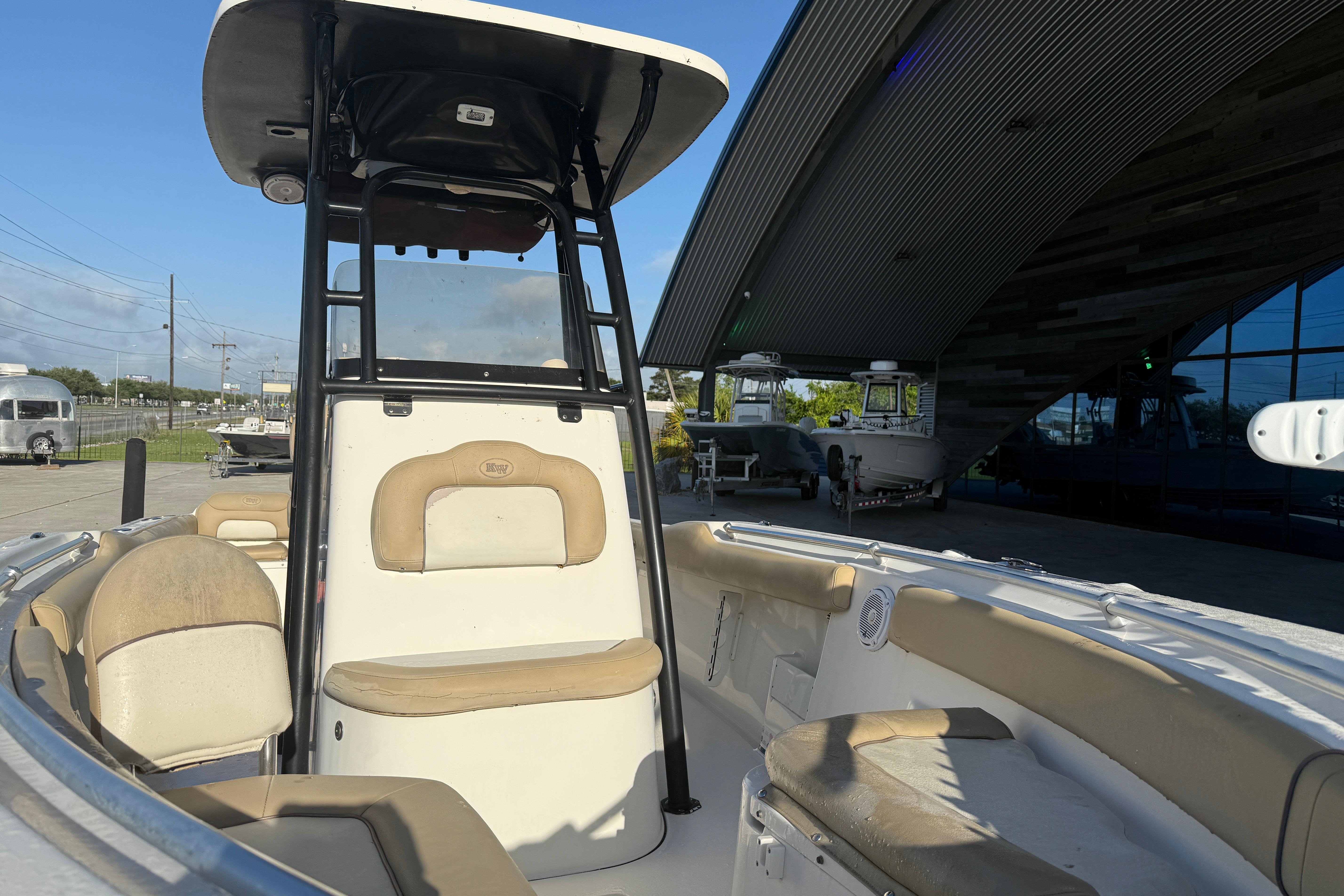 2016 Key West 239 FS boat interior with seating and console, parked near a modern building.